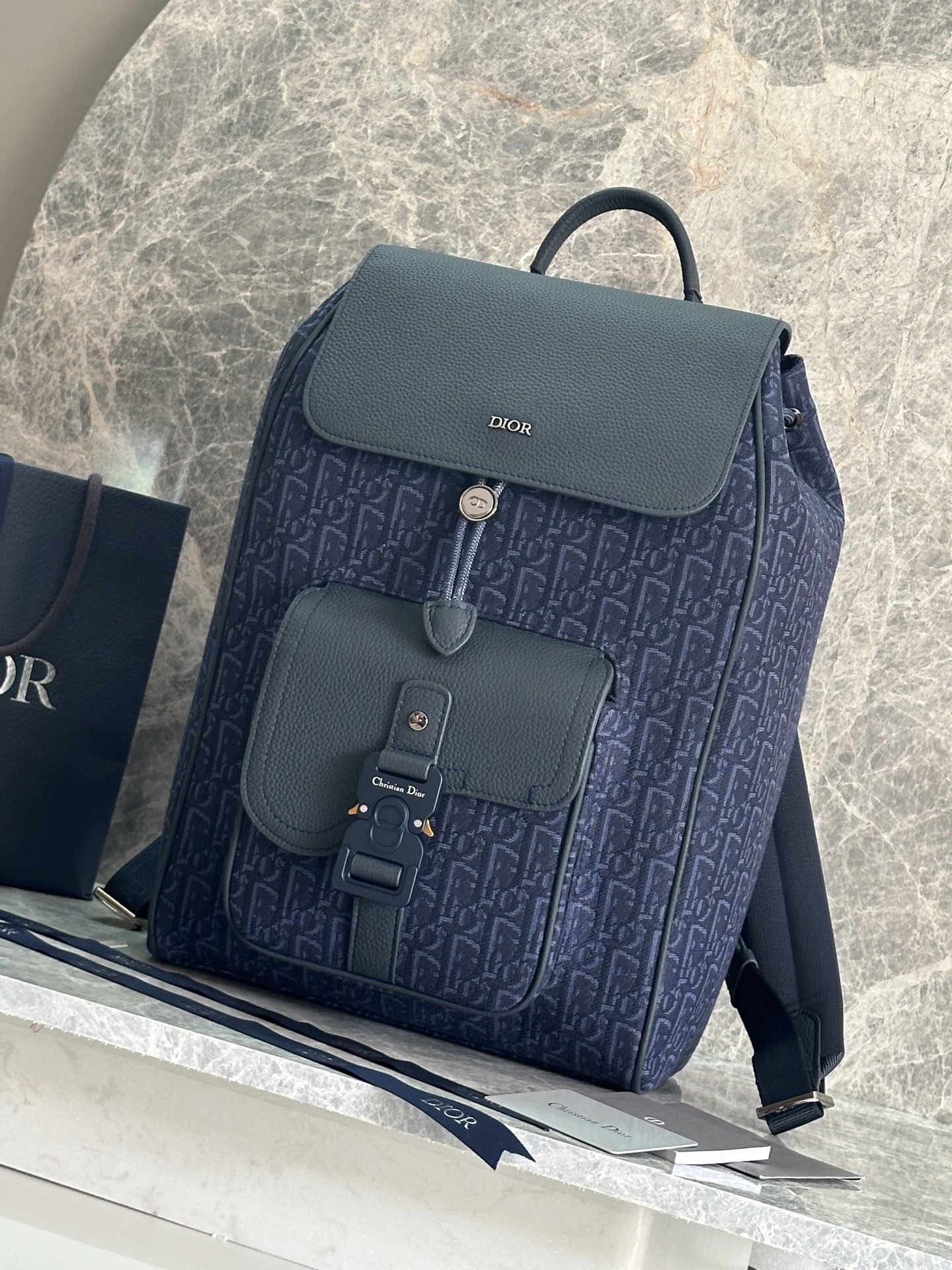 NO:386417,This saddle backpack is a new product for men's fall 2024. It uses a stylish original design to highlight the saddle style. It is carefully crafted from beige and black Oblique printed fabrics, decorated with black grained cowhide leather details, and the front is embellished with Dior logo. It is spacious and has a compartment to hold a variety of daily necessities. The front saddle flip pocket is paired with aluminum buckles, which can hold a wallet, keys, headphones or mobile phones for easy access. It is practical and versatile and is the finishing touch of all kinds of styling. The main compartment is paired with magnetic flip cover and drawstring. The interior laptop flat compartment Front saddle flip pocket is paired with CD logo aluminum buckle Leather top handle Adjustable padded shoulder straps Back with padded mesh fabric adorned with Dior logo Metal cladding on the front Dior logo Dior logo Inside with Dior embossed logo on the inside  Dust bags included Made in Italy Size 26.5 x 41 x 14 cm (L x H x W) Main compartment can hold 1 15-inch laptop, files and 1 tablet Weight 961 g Model 93392 Blue cloth, Dior, Dior, Dior, Wallets, backpacks, cowhide19860909这款马鞍双肩背包是二零二四秋季男装系列新品,采用时尚的原创设计,突显马鞍风格.采用米色和黑色 Oblique 印花面料精心制作,饰以黑色粒面牛皮革细节,正面点缀以 Dior 标志.空间宽敞,设有一个隔层,可收纳各种日常用品,正面马鞍翻盖口袋搭配铝扣,可收纳钱包、钥匙、耳机或手机,便于轻松取用.实用百搭,是各式造型的点睛之笔. 主隔层搭配磁性翻盖和抽绳 内部笔记本电脑扁平隔层 正面马鞍翻盖口袋搭配 CD 标志铝扣 皮革顶部手柄 可调节加垫肩带 背部采用加垫网眼织物,饰以 Dior 标志 正面金属覆层黄铜 Dior 标志 内侧饰有 Dior 压花标志 内含防尘袋 意大利制造尺寸26.5 x 41 x 14 厘米（长 x 高 x 宽） 主隔层可收纳 1 台 15 英寸笔记本电脑、文件和 1 台平板电脑 重量961 克 型号93392蓝色布,迪奥,dior,dior,wallets,backpacks,cowhide,Bag