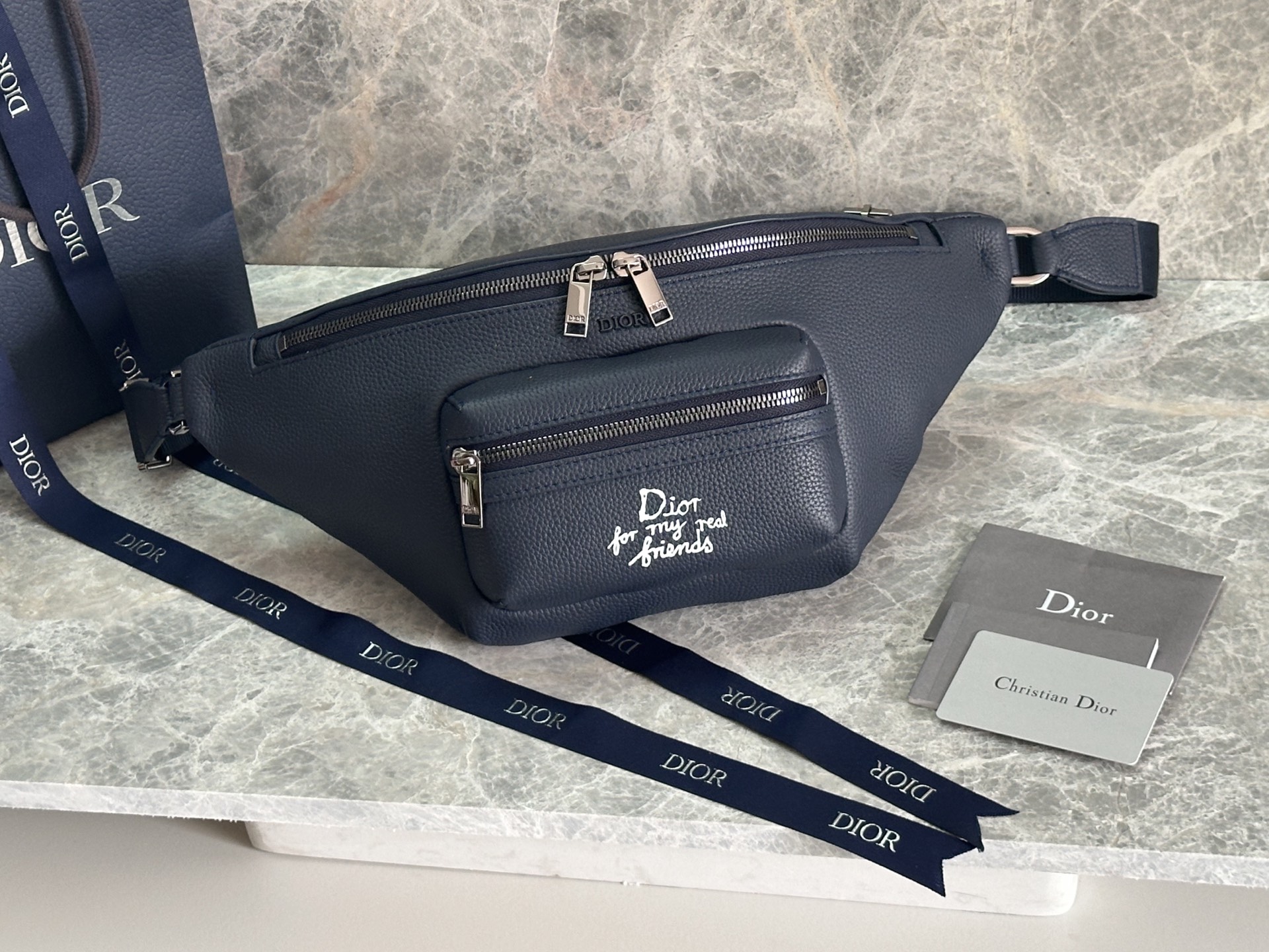 NO:386442,P This Rider 2.0 waist bag comes from the DIOR AND HYLTON NEL limited series. It is carefully crafted from navy blue grain cowhide leather and other materials. The front zipper pocket is decorated with a white Dior For My Real Friends logo printed from the DIOR AND HYLTON NEL co-branded series to enhance the style. The zipper main compartment can accommodate various daily necessities, paired with an adjustable strap, and can be cross-body. Model 93912 blue leather Size 39×17×11.5 cm Main body: cowhide leather, technology fabric. Lining material: technology fabric, cotton, cowhide leather zipper main compartment internal insert pocket, front zipper pocket, adjustable Christian  Dior logo nylon jacquard and cowhide leather shoulder straps with vintage silver finish copper alloy Dior logo interior with DIOR AND HYLTON NEL embossed logo containing dust bags, Dior, dior, dior, cowhide19860909P 这款 Rider 2.0 腰包来自DIOR AND HYLTON NEL 限定系列.采用海军蓝色粒面牛皮革等材质精心制作,正面拉链口袋饰以来自 DIOR AND HYLTON NEL联名系列的白色Dior For My Real Friends 标志印花提升格调.拉链主隔层可收纳各种日常用品,搭配可调节带,可斜挎. 型号93912蓝皮 尺寸39×17×11.5厘米 主体:牛皮革,科技面料.里料:科技面料,棉,牛皮革拉链主隔层内部插袋,正面拉链口袋,可调节的Christian Dior标志尼龙提花和牛皮革肩带正面饰以复古银色饰面铜合金Dior标志 内部饰有 DIOR AND HYLTON NEL 压花标志内含防尘袋,迪奥,dior,dior,cowhide,Bag