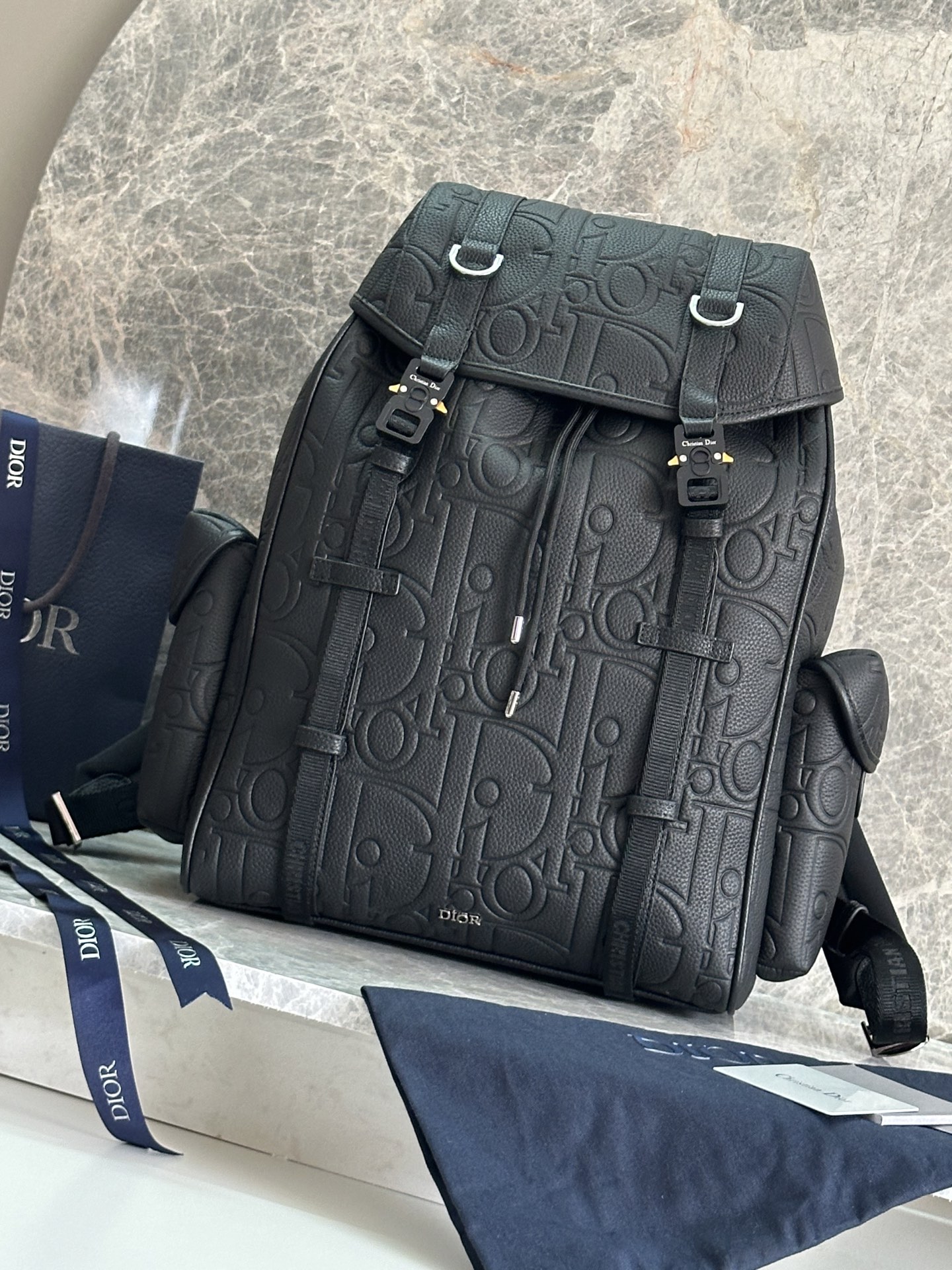 NO:213539,P This Dior Hit The Road flip backpack combines modern style with the high-order spirit of Dior. It is carefully crafted from black Oblique printed fabrics and other materials, decorated with grained cowhide leather details to enhance the style, and the front is decorated with Dior logo. The flip is paired with CD logo mini aluminum buckles and two Christian Dior logo nylon jacquard tapes. It has a spacious main compartment and two side magnetic flip pockets. It is practical and versatile, adding the finishing touch to all kinds of casual looks. Fabric fabric, lining fabric, decorative and decorative lines, main compartment is matched with flip and drawstring, tone CD logo mini aluminum buckle and D-shaped trim internal flat computer compartment Side magnetic flip pocket Top leather handle  Adjustable padded shoulder straps Padded mesh fabric on the back, decorated with Dior logo, front with metal clad copper alloy Dior logo, interior with Dior embossed logo, included dust bag Made in Italy Dimensions 43 x 43 x 18 cm (L x H x W) Main compartment can hold 1 15-inch laptop, A4 files and 1 tablet Side pockets can hold various models of mobile phone models: FK-1ESBA205YKY, Dior, dior, backpacks, cowhide19860909P 这款 Dior Hit The Road 翻盖双肩背包将现代风格与 Dior 的高订精神融为一体.采用黑色 Oblique 印花面料等材质精心制作,饰以同色调粒面牛皮革细节提升格调,正面点缀以 Dior 标志.翻盖搭配 CD 标志迷你铝扣和两条 Christian Dior 标志尼龙提花饰带,内设宽敞主隔层,搭配两个侧面磁性翻盖口袋.实用百搭,为各式休闲造型增添点睛之笔. 面料织物 里料织物 装饰物及装饰线除外 主隔层搭配翻盖和抽绳 同色调 CD 标志迷你铝扣和 D 形饰环 内部扁平电脑隔层 侧面磁性翻盖口袋 顶部皮革手柄 可调节加垫肩带 背部采用加垫网眼织物,饰以 Dior 标志 正面饰以金属覆层铜合金 Dior 标志 内部饰有 Dior 压花标志 内含防尘袋 意大利制造 尺寸43 x 43 x 18 厘米（长 x 高 x 宽） 主隔层可收纳 1 部 15 英寸笔记本电脑、A4 文件和 1 部平板电脑 侧面口袋可收纳各种型号的手机型号:FK-1ESBA205YKY,迪奥,dior,dior,backpacks,cowhide,Bag