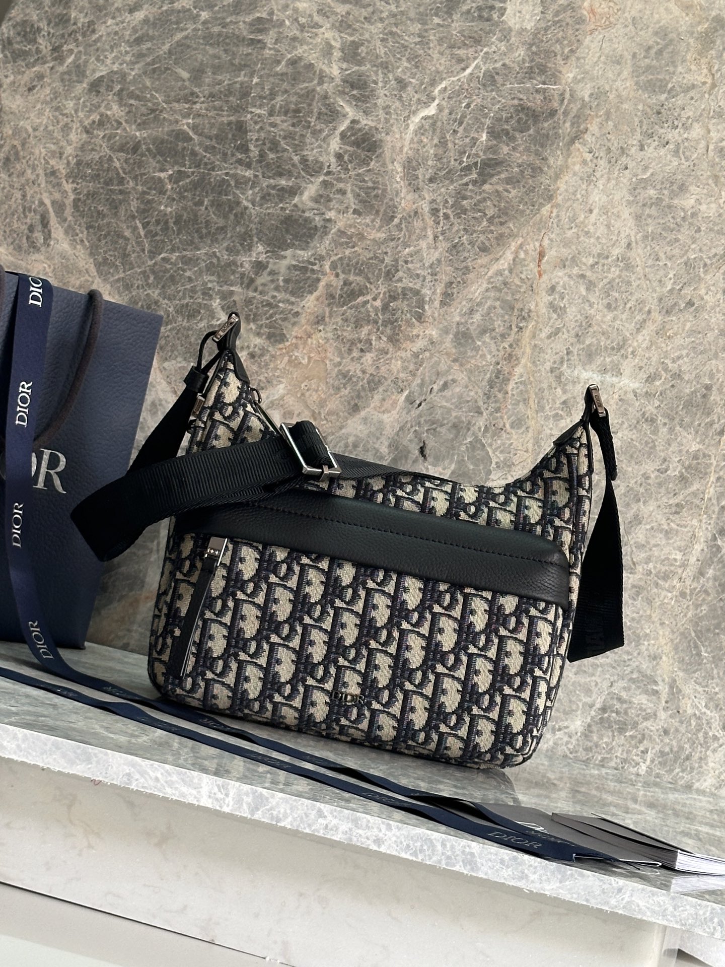 NO:556537,P Top Original Order This Rider Soft dumpling bag is a new product in the 2025 autumn men's wear series, combining practical functions and fashionable design. It is carefully made of materials such as beige and black Oblique printed fabrics, and is decorated with black grained cow leather details to enhance the style. It has a zipper compartment and a front zipper pocket to store various daily necessities. Small practical style, with adjustable shoulder strap, can be carried on the shoulder or crossbody. Main body cotton, technical fabric, cow leather  Lining in technical fabric, cotton, cow leather Main compartment with zip Internal slip pocket Front zip pocket Adjustable Christian Dior signature nylon jacquard shoulder strap Metal-coated copper alloy Dior signature on the front Dior embossed signature on the interior Dust bag included Made in Italy Dimensions 25 x 22 x 9 cm (L x   Height19860909P 顶级原单 这款 Rider Soft 水饺包是二零二五秋季男装系列新品,兼具实用功能与时尚设计.采用米色和黑色 Oblique 印花面料等材质精心制作,饰以黑色粒面牛皮革细节提升格调.设有拉链隔层和正面拉链口袋,可收纳各种日常用品.小号实用款式,搭配可调节肩带,可肩背或斜挎. 主体棉,科技面料,牛皮革 里料科技面料,棉,牛皮革 拉链主隔层 内部插袋 正面拉链口袋 可调节的 Christian Dior 标志尼龙提花肩带 正面饰以金属覆层铜合金 Dior 标志 内部饰有 Dior 压花标志 内含防尘袋 意大利制造 尺寸25 x 22 x 9 厘米（长 x 高 x 宽） 主隔层可收纳 2 部手机 肩带长度59.5 - 108.5 厘米 肩带顶端至手袋顶端长度31.5 - 57.5 厘米 型号93919蓝布 黑布,迪奥,dior,dior,cowhide,Bag