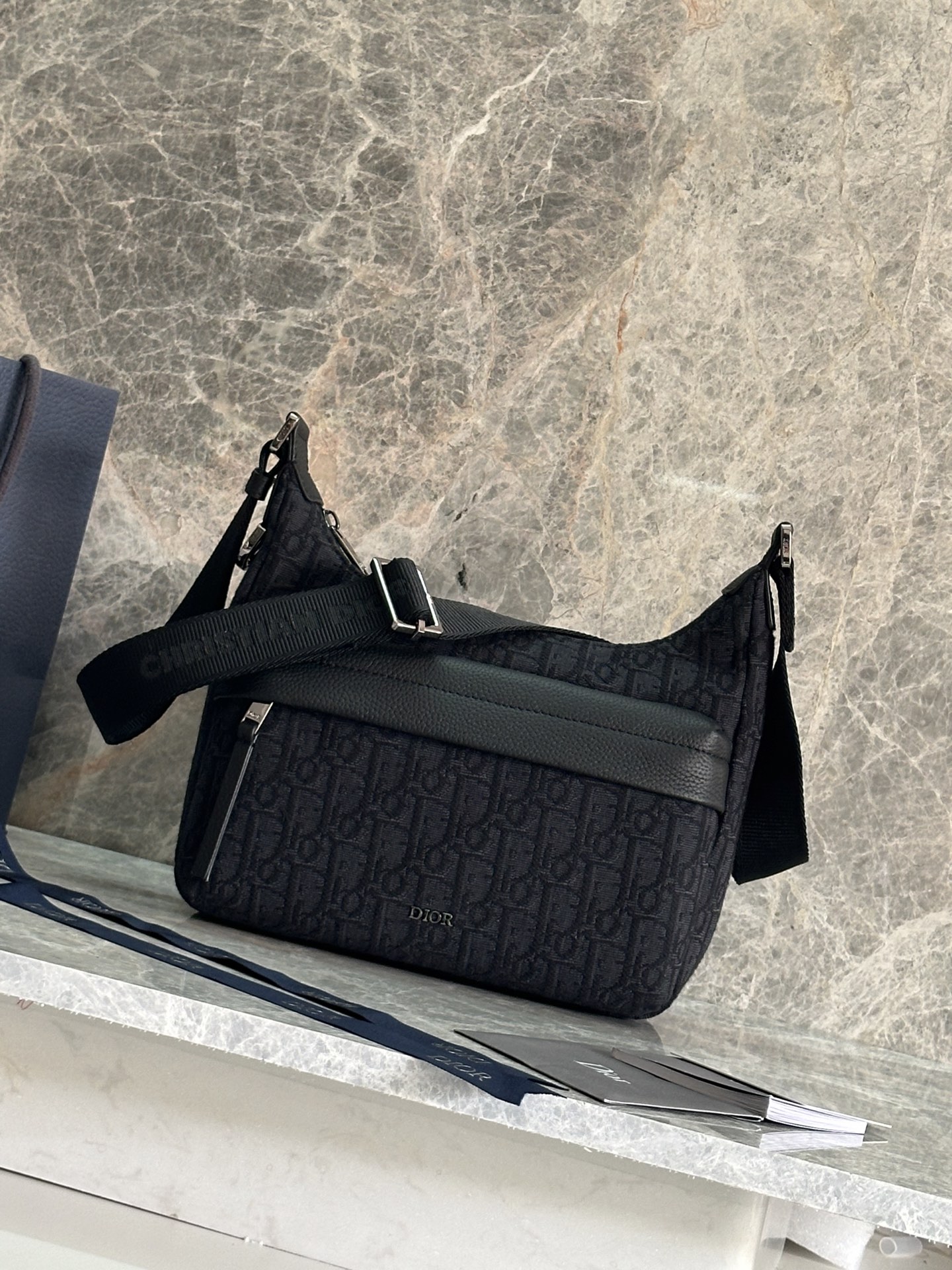 NO:556526,P Top original order This Rider Soft dumpling bag is a new product in the 2025 autumn men's wear series, combining practical functions and fashionable design. It is carefully made of beige and black Oblique printed fabrics and other materials, and decorated with black grained cow leather details to enhance the style. It has a zipper compartment and a front zipper pocket to store various daily necessities. Small practical style, with adjustable shoulder strap, can be carried on the shoulder or crossbody. Main body cotton, technical fabric, cow leather  Lining in technical fabric, cotton, cow leather Main compartment with zip Internal slip pocket Front zip pocket Adjustable Christian Dior signature nylon jacquard shoulder strap Metal-coated copper alloy Dior signature on the front Dior embossed signature on the interior Dust bag included Made in Italy Dimensions 25 x 22 x 9 cm (L x   Height19860909P 顶级原单这款 Rider Soft 水饺包是二零二五秋季男装系列新品,兼具实用功能与时尚设计.采用米色和黑色 Oblique 印花面料等材质精心制作,饰以黑色粒面牛皮革细节提升格调.设有拉链隔层和正面拉链口袋,可收纳各种日常用品.小号实用款式,搭配可调节肩带,可肩背或斜挎. 主体棉,科技面料,牛皮革 里料科技面料,棉,牛皮革 拉链主隔层 内部插袋 正面拉链口袋 可调节的 Christian Dior 标志尼龙提花肩带 正面饰以金属覆层铜合金 Dior 标志 内部饰有 Dior 压花标志 内含防尘袋 意大利制造 尺寸25 x 22 x 9 厘米（长 x 高 x 宽） 主隔层可收纳 2 部手机 肩带长度59.5 - 108.5 厘米 肩带顶端至手袋顶端长度31.5 - 57.5 厘米 型号93919蓝布 黑布,迪奥,dior,dior,cowhide,Bag