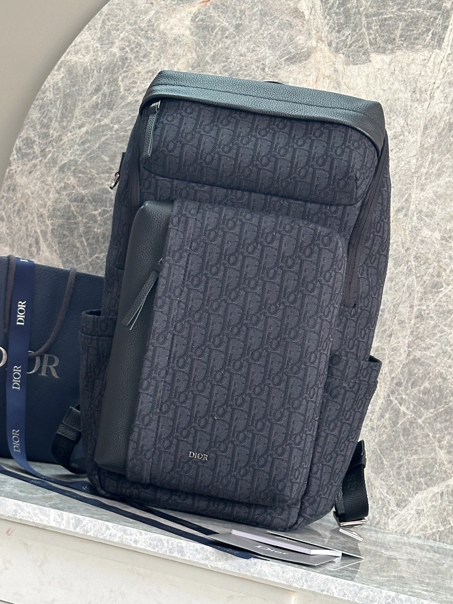 NO:556484,P This Rider Soft zippered backpack is a new product in the 2025 autumn men's wear series. It combines fashionable design with practical functions. It is carefully made of black Oblique printed fabric and other materials, decorated with tonal grained cow leather details to enhance the style, and embellished with the Dior logo. It has a large open zipper compartment, internal slip pockets, two front zipper pockets and two side slip pockets, which can store a variety of daily necessities. Paired with D  Shaped ring for hanging various accessories. Adjustable padded shoulder strap makes it more sophisticated, making it an ideal daily companion. Body cotton, technical fabric, cow leather Lining technical fabric, cotton, cow leather Zippered main compartment Internal flat computer compartment Internal slip pockets 2 front zipper pockets 2 side slip pockets D-shaped ring for hanging various accessories Top leather handle   Adjustable padded shoulder straps Padded mesh back with Dior signature Metal-coated copper alloy Dior signature on the front Embossed Dior signature on the interior Dust bag included Made in Italy Dimensions 32 x 46 x 17.5 cm (L x H x W) Main compartment can hold 1 15' laptop, A4 files and 1 tablet Model number: 93922 Black cloth  Blue cloth, Dior, dior, dior, backpacks, cowhide19860909P 这款 Rider Soft 拉链双肩背包是二零二五秋季男装系列新品,兼具时尚设计与实用功能.采用黑色 Oblique 印花面料等材质精心制作,饰以同色调粒面牛皮革细节提升格调,点缀以 Dior 标志.设有宽大开口拉链隔层、内部插袋、两个正面拉链口袋和两个侧面插袋,可收纳各种日常用品.搭配 D 形饰环,可悬挂各种配饰.搭配可调节的加垫肩带更显精致,是日常的理想良伴. 主体棉,科技面料,牛皮革 里料科技面料,棉,牛皮革 拉链主隔层 内部扁平电脑隔层 内部插袋 2 个正面拉链口袋 2 个侧面插袋 D 形饰环,可悬挂各种配饰 顶部皮革手柄 可调节加垫肩带 背部采用加垫网眼织物,饰以 Dior 标志 正面饰以金属覆层铜合金 Dior 标志 内部饰有 Dior 压花标志 内含防尘袋 意大利制造尺寸32 x 46 x 17.5 厘米（长 x 高 x 宽） 主隔层可收纳 1 部 15 英寸笔记本电脑、A4 文件和 1 部平板电脑 型号:93922 黑布 蓝布,迪奥,dior,dior,backpacks,cowhide,Bag