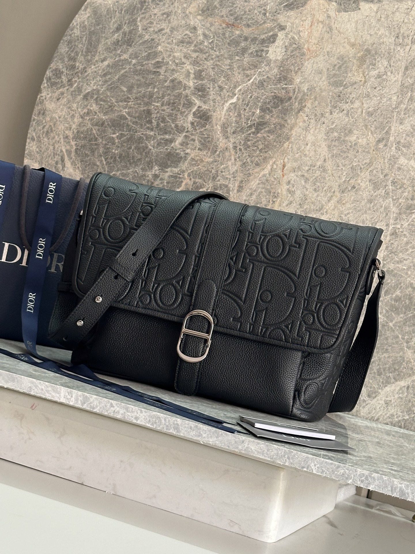 NO:395124,P Large Dior Daily Flip Messenger Bag Number: 1ESME197LLG_93923 This Dior Daily Flip Messenger Bag is a new product in the autumn 2025 men's clothing series, showing an elegant and practical design. The Dior Gravity printed leather uses embossing technology to present classic patterns on black cowhide leather, highlighting the exquisite craftsmanship of the Dior Workshop. The flip is decorated with a magnetic Dior Daily buckle interpreted from the CD's first letter to enhance the style, with a spacious compartment. There is a zippered pocket on the front and back sides, which makes it more refined. Large style, paired with adjustable shoulder straps, can be worn on the shoulder or crossbody, which can add a high-order style to various shapes. Body cowhide leather Lining technology fabric, cotton, cowhide leather  Main compartment with flap and Dior Daily buckle 3 internal pockets Front zipper pocket Rear zipper pocket Adjustable leather shoulder straps Internal with Dior embossed logo Dust bag included Dimensions 31 x 25 x 13 cm (L x H x W) Main compartment can hold 1 13-inch laptop, A4 file and 1 tablet Strap length 112 - 133 cm Strap top to top 47 - 58 cm, Dior, dior, dior, cowhide19860909P 大号 Dior Daily 翻盖信使包 编号:1ESME197LLG_93923 这款 Dior Daily 翻盖信使包是二零二五秋季男装系列新品,展现优雅实用的设计.Dior Gravity 印花效果皮革采用压花工艺将经典图案精致地呈现于黑色牛皮革之上,彰显 Dior 工坊的精湛工艺.翻盖饰以从 CD 首字母演绎而来的磁性 Dior Daily 搭扣提升格调,内设一个宽敞的隔层.正面和后侧设有拉链口袋,更显精致.大号款式,搭配可调节的肩带,可肩背或斜挎,可为各式造型增添高订风范. 主体牛皮革 里料科技面料,棉,牛皮革 主隔层搭配翻盖和 Dior Daily 搭扣 3 个内部插袋 正面拉链口袋 后侧拉链口袋 可调节的皮革肩带 内部饰有 Dior 压花标志 内含防尘袋 尺寸31 x 25 x 13 厘米（长 x 高 x 宽） 主隔层可收纳 1 部 13 英寸笔记本电脑、A4 文件和 1 部平板电脑 肩带长度112 - 133 厘米 肩带顶端至手袋顶端长度47 - 58 厘米,迪奥,dior,dior,cowhide,Bag