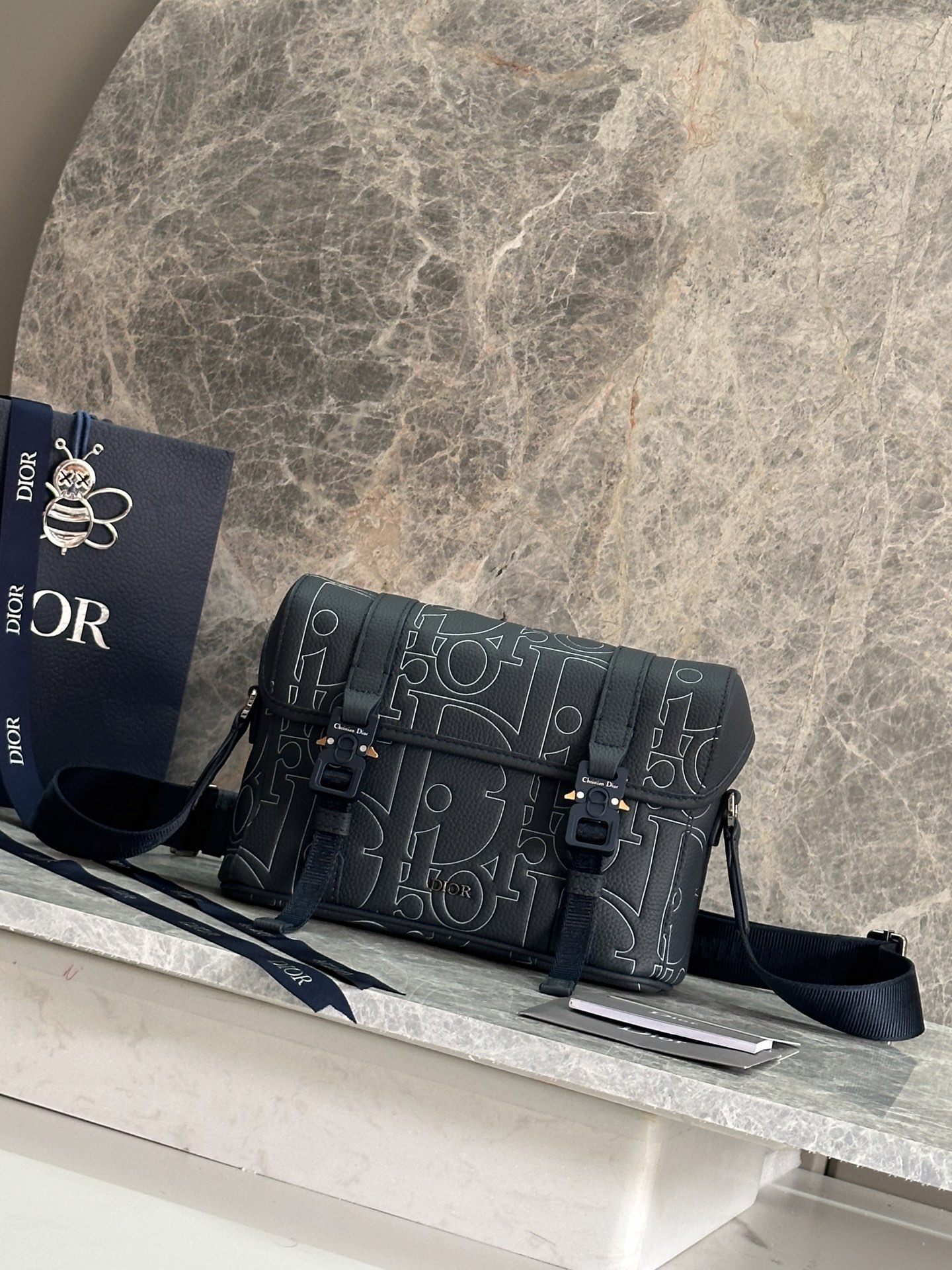 NO:395121,53[fa][fa][fa][fa][fa]This flip messenger bag highlights the high-order spirit of Dior with a modern and fashionable design, further enriching the Dior Hit The Road series. It is carefully crafted from navy blue Dior Gravity Outline leather and other materials. It is an embossed grained cowhide leather with 3D effect Dior classic pattern to highlight the charm of the graphic. The front is embossed with Dior logo, and the flip is decorated with the same tone CD mini aluminum buckle and two Christian Dior nylon jacquard strips. The compartment is spacious and can accommodate a variety of daily necessities. The style is practical and matched with adjustable shoulder straps, which can add the finishing touch to the casual outfit. Body cowhide, tech fabric Lining tech fabric, cotton, cowhide The main compartment is matched with flip and tone CD Mini aluminum buckle Internal insert bag Adjustable Christian Dior logo nylon jacquard and cowhide shoulder straps Metal clad copper alloy Dior logo Internal embossed with Dior embossed logo Dust bags included Made in Italy Dimensions 24 x 18 x 8 cm (L x H x W) Number: 1HTO333LG93398 Blue leather, Dior, dior, dior, cowhide1986090953[發][發][發]这款翻盖信使包以现代时尚的设计突显 Dior 的高订精神,进一步丰富 Dior Hit The Road 系列.采用海军蓝色 Dior Gravity Outline 皮革等材质精心制作,这是一种压花粒面牛皮革,饰以 3D 效果 Dior 经典图案,彰显图形魅力.正面点缀以 Dior 标志,翻盖饰以同色调 CD 迷你铝扣和两条 Christian Dior 尼龙提花饰带.隔层宽敞,可收纳各种日常用品.款式实用,搭配可调节肩带,可为休闲装扮增添点睛之笔. 主体牛皮革,科技面料 里料科技面料,棉,牛皮革 主隔层搭配翻盖和同色调 CD 迷你铝扣 内部插袋 可调节的 Christian Dior 标志尼龙提花和牛皮革肩带 正面饰以金属覆层铜合金 Dior 标志 内部饰有 Dior 压花标志 内含防尘袋 意大利制造 尺寸24 x 18 x 8 厘米（长 x 高 x 宽） 编号: 1HTO333LG93398蓝皮,迪奥,dior,dior,cowhide,Bag