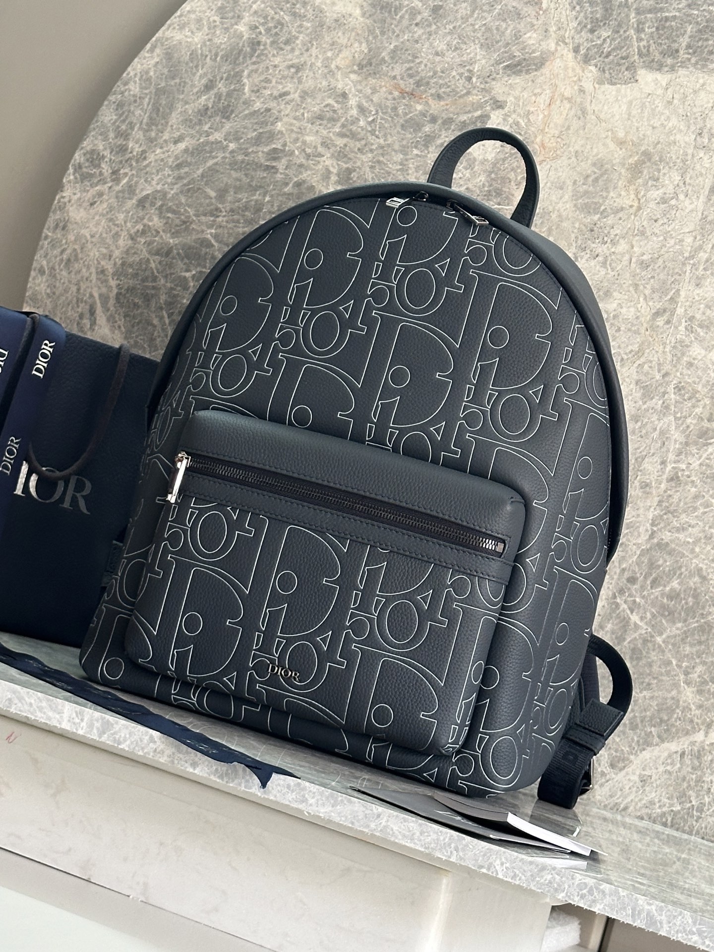 NO:395117,P This Rider 2.0 zippered backpack is a new version of Dior's classic item. It is carefully crafted from navy blue Dior Gravity Outline leather and other materials. It is an embossed grained cowhide leather with 3D effects Dior classic pattern to highlight the graphic charm, and the front is embossed with a Dior logo. Zipper closure and adjustable padded shoulder straps are an ideal accessory for daily life. Body cowhide leather, technology fabric Lining tech fabric, cotton, cowhide leather Zipper main compartment Internal flat computer compartment Internal insert pocket Front zipper pocket Top leather handle Adjustable padded shoulder strap Back with padded mesh fabric adorned with Dior logo Front with metal clad copper alloy Dior logo Internal embossed with Dior logo  Dust bags included Made in Italy Dimensions 32 x 43 x 19 cm (L x H x W) Number: 1ESBA-93328 Blue leather Main compartment can store 1 15-inch laptop, A4 file and 1 tablet, Dior, Dior, backpacks, cowhide19860909P 这款 Rider 2.0 拉链双肩背包为 Dior 的经典单品推出全新版本.采用海军蓝色 Dior Gravity Outline 皮革等材质精心制作,这是一种压花粒面牛皮革,饰以 3D 效果 Dior 经典图案,彰显图形魅力,正面点缀以 Dior 标志.拉链开合,搭配可调节的加垫肩带,是日常生活的理想配饰. 主体牛皮革,科技面料 里料科技面料,棉,牛皮革 拉链主隔层 内部扁平电脑隔层 内部插袋 正面拉链口袋 顶部皮革手柄 可调节加垫肩带 背部采用加垫网眼织物,饰以 Dior 标志 正面饰以金属覆层铜合金 Dior 标志 内部饰有 Dior 压花标志 内含防尘袋 意大利制造 尺寸32 x 43 x 19 厘米（长 x 高 x 宽） 编号: 1ESBA一93328蓝皮 主隔层可收纳 1 部 15 英寸笔记本电脑、A4 文件和 1 部平板电脑,迪奥,dior,dior,backpacks,cowhide,Bag