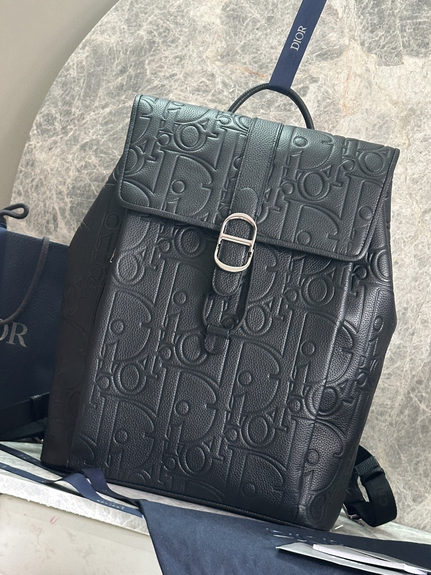 NO:395131,P Genuine development Dior Daily flip backpack No.: 1ESBA231LLG_93928 This Dior Daily flip backpack is a new product in the autumn men's clothing series of 2025, showing an elegant and practical design. Dior Gravity printed leather uses embossing technology to present classic patterns on black cowhide leather, highlighting the exquisite craftsmanship of Dior Workshop. The flip is decorated with a magnetic Dior Daily buckle interpreted from the CD's first letter to enhance the style and has a spacious compartment. The style is fashionable and matched with the front zipper pocket to make it look more refined, which can add a high-order style to all kinds of outfits. Main technology fabric, cowhide leather lining technology fabric, cotton, cowhide leather flip main compartment, Dior Daily  Buckle and drawstring Interior flat computer compartment 4 internal insert pockets Front zipper pocket Top handle Adjustable padded shoulder straps Back with padded mesh fabric decorated with Dior logo Interior with Dior embossed logo Interior with dust bag size 30.5 x 41.5 x 15.5 cm (L x H x W) Main compartment can hold 1 15-inch laptop, A4 file and 1 tablet Weight 1.6 kg Dimensions and weight details may vary depending on product material, Dior, dior, backpacks, cowhide19860909P  正品开发Dior Daily 翻盖双肩背包 编号:1ESBA231LLG_93928 这款 Dior Daily 翻盖双肩背包是二零二五秋季男装系列新品,展现优雅实用的设计.Dior Gravity 印花效果皮革采用压花工艺将经典图案精致地呈现于黑色牛皮革之上,彰显 Dior 工坊的精湛工艺.翻盖饰以从 CD 首字母演绎而来的磁性 Dior Daily 搭扣提升格调,内设一个宽敞的隔层.款式时尚,搭配正面拉链口袋更显精致,可为各式装扮增添高订风范. 主体科技面料,牛皮革 里料科技面料,棉,牛皮革 翻盖主隔层、Dior Daily 搭扣和抽绳 内部扁平电脑隔层 4 个内部插袋 正面拉链口袋 顶部手柄 可调节加垫肩带 背部采用加垫网眼织物,饰以 Dior 标志 内部饰有 Dior 压花标志 内含防尘袋尺寸30.5 x 41.5 x 15.5 厘米（长 x 高 x 宽） 主隔层可收纳 1 部 15 英寸笔记本电脑、A4 文件和 1 部平板电脑 重量1.6 千克 尺寸和重量详情可能因产品材质而有所不同,迪奥,dior,dior,backpacks,cowhide,Bag