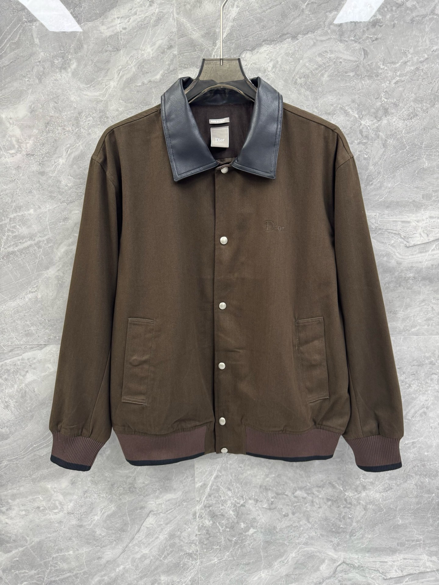 NO:817509,The new CD twill cotton lapel baseball jacket for spring and summer 26 is based on a classic retro silhouette and combines the sophistication of high fashion with the relaxed feeling of street casualness. The lapel is spliced with fine leather, which creates a material collision with the cotton body and is neat.  The snap button placket and double side patch pockets combine practicality and visual order; the ribbed cuffs and hem are finished with contrasting details, which not only enhances the retro sports atmosphere, but also fits the body shape, locks in temperature, and is easily suitable for daily commuting and light social occasions.  The body of the garment is made of high-count twill cotton fabric, which feels solid and crisp yet soft. The delicate texture on the surface gives the garment a high-end matte texture. The upper body is breathable, comfortable and not easily deformed. The details and craftsmanship show the brand's ingenuity. The chest is in the same color.  The CD embroidery is low-key and restrained, the brand logo is engraved on the back of the leather collar to enhance recognition, the metal snaps are engraved with a dark pattern of CD letters, and the precision stitching and hemming are neat and neat. Every detail conveys CD's ultimate pursuit of quality.  The overall style wanders between retro elegance and modern trends. The dark brown tone is calm and atmospheric, and the dark green tone is retro and eye-catching. Both colors can be easily integrated into multiple dressing contexts. It can be worn with a turtleneck sweater and trousers to create a light and luxurious business look; it can also be layered with a T-shirt and overalls to unlock a casual street feel. Whether worn alone in spring and autumn or as an inner layer in winter, it can highlight the wearer's taste and style. It is a core item in the wardrobe that combines classic heritage and contemporary aesthetics. Size M-2XL  Color Dark Green Brown M Size Bust 120 Shoulder Width 51 Sleeve Length 61 Clothes Length 71 L Size Chest 124 Shoulder Width 52 Sleeve Length 62 Clothes Length 72 XL Bust 128 Shoulder Width 54 Sleeve Length 63 Clothes Length 74 2  Wear size M if you are under 135 pounds, wear size L if you are 135-150 pounds, wear size XL if you are 150-170 pounds, wear size 2XL if you are 170-185 pounds, Dior-clothing, dior, jackets & coats, tees, t-shirts,1986090926春夏新款CD斜纹棉翻领棒球服夹克,以经典复古廓形为基底,融合高级时装的精致感与街头休闲的松弛感.翻领采用细腻皮革拼接,与棉质衣身形成材质碰撞,利落的按扣门襟与双侧贴袋兼顾实用性与视觉秩序感；罗纹袖口与下摆以撞色细节收尾,既强化了复古运动氛围,又能贴合身形、锁住温度,轻松适配日常通勤与轻社交场合. 衣身选用高支斜纹棉质面料,触感扎实挺括却不失柔软度,表面细腻的肌理感赋予衣物高级哑光质感,上身透气舒适且不易变形.细节工艺尽显品牌匠心胸前同色系CD刺绣低调内敛,皮革领后印刻品牌标识强化辨识度,金属按扣镌刻CD字母暗纹,精密车线与包边处理工整利落,每一处细节都传递出CD对品质的极致追求. 整体风格游走于复古优雅与现代潮流之间,深棕色调沉稳大气、墨绿色调复古吸睛,两种配色均能轻松融入多元穿搭语境.可内搭高领针织衫与西裤,打造轻奢商务造型；也可叠搭T恤与工装裤,解锁随性街头感,无论是春秋单穿还是冬季作为内搭,都能彰显穿着者的品味与格调,是兼具经典底蕴与当代审美衣橱核心单品.尺码M-2XL 颜色墨绿色 棕色 M码 胸围120 肩宽51 袖长61 衣长71 L码 胸围124 肩宽52 袖长62 衣长72 XL码胸围128 肩宽54 袖长63 衣长74 2XL码 胸围132 肩宽55 袖长64 衣长75 尺码推荐 135斤以内穿M码,135-150斤穿L码,150-170斤穿XL码,170-185斤穿2XL码,迪奥-服装,dior,jackets & coats,tees，t-shirt,,Women's clothing