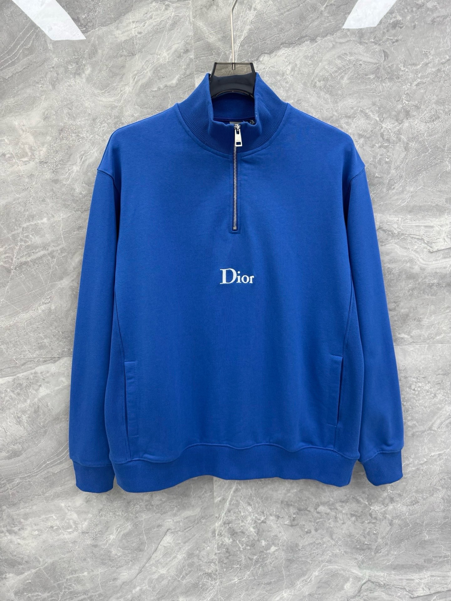NO:817504,The new CD half-zip sweatshirt for spring and summer 26 is engraved with the brand's genes with the classic embroidered logo, and the Klein blue and dark green colors bring a high-end atmosphere. The soft and skin-friendly cotton blended fabric is selected, with fine texture and outstanding drape. It not only retains the casual and relaxed feel of the sweatshirt, but also hides the exquisite luster of light luxury fabrics, making it a low-key daily choice to show your taste.  The half-zipper cut of the stand-up collar is matched with a metal zipper puller engraved with the CD logo to create neat layers between opening and closing. The loose shoulder design is compatible with a variety of body shapes. The symmetrical pockets on both sides balance practicality and visual balance. The ribbed collar, cuffs and hem are gathered together to ensure a good fit and make the overall silhouette more neat and crisp, making it easily suitable for casual outings and light business scenes.  From the precise and neat embroidery stitching to the metal zipper details engraved with the brand logo, every detail demonstrates the craftsmanship of CD. Without complicated decoration, only the minimalist colors, iconic logos and elegant hardware details convey the 'luxury in the invisible' dressing philosophy, making this sweatshirt a wardrobe staple that spans seasons and adapts to a variety of styles. Sizes M-2XL Color Blue Green M Size Bust 116 Shoulder Width 50 Sleeve Length 61  Length 70 L, bust 120, shoulder width 51, sleeve length 62, length 72 XL, bust 124, shoulder width 53, sleeve length 64, length 73 2  Wear size M if you are under 135 pounds, wear size L if you are 135-155 pounds, wear size XL if you are 155-175 pounds, wear size 2XL if you are 175-195 pounds, Dior-clothing, dior, hoodie, sweatshirts,1986090926春夏新款CD半拉链卫衣,以经典刺绣徽标镌刻品牌基因,克莱因蓝与墨绿配色自带高级氛围感.甄选柔软亲肤的棉质混纺面料,肌理细腻且垂坠感出众,既保留了卫衣的休闲松弛感,又暗藏轻奢面料的精致光泽,是低调彰显品味的日常之选. 立领半拉链剪裁搭配刻有CD标识的金属拉链头,在开合间塑造利落层次,宽松落肩版型兼容多元身形,两侧对称插袋兼顾实用性与视觉平衡.罗纹领口、袖口与下摆的收束工艺,既保证了穿着的贴合度,又让整体廓形更显利落挺括,轻松适配休闲出街与轻商务场景. 从精密工整的刺绣针脚,到刻有品牌标识的金属拉链细节,每一处都彰显着CD的匠心工艺.无需繁复装饰,仅凭极简的色彩、标志性的徽标与考究的五金细节,便传递出“奢华于无形”的穿搭哲学,让这件卫衣成为跨越季节、适配多种风格的衣橱 staple.尺码M-2XL 颜色蓝色 绿色 M码胸围116 肩宽50 袖长61 衣长70 L码 胸围120 肩宽51 袖长62 衣长72 XL码 胸围124 肩宽53 袖长64 衣长73 2XL码 胸围130 肩宽54 袖长65 衣长74 尺码推荐 135斤以内穿M码,135-155斤穿L码,155-175斤穿XL码,175-195斤穿2XL码,迪奥-服装,dior,hoodie,sweatshirts,,Women's clothing