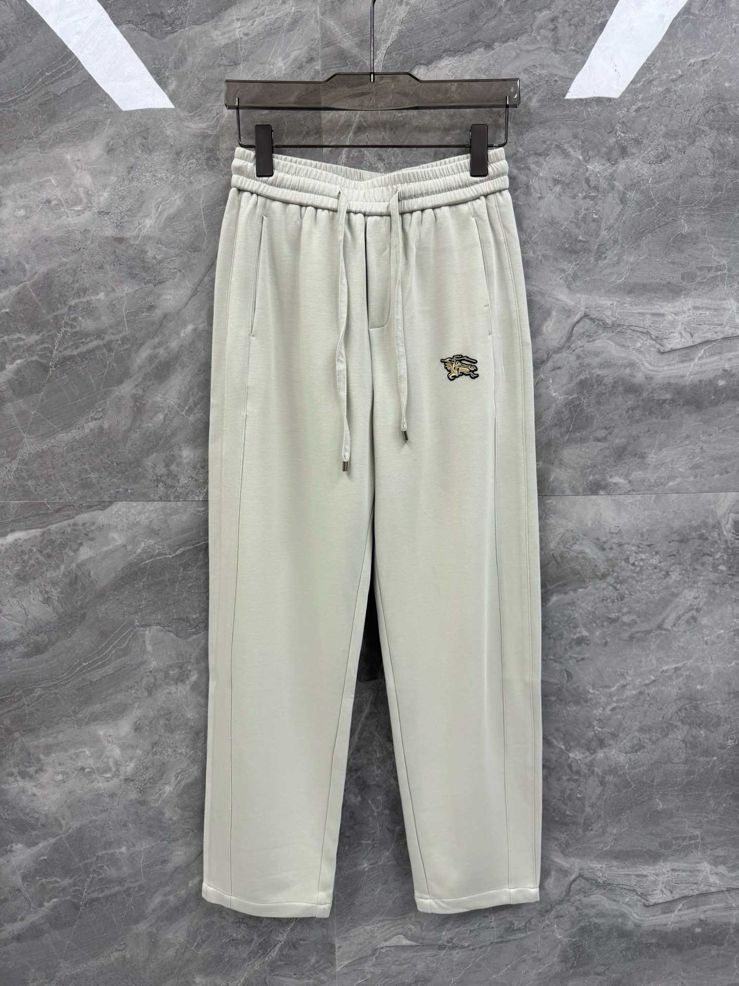 NO:817492,26 new spring and summer BBR embroidered war horse logo versatile casual pants, men's light luxury minimalist style drawstring sweatpants. Exclusive channel recommendation, high-end knitted cotton blended fabric, super classic and representative casual sweatpants style, excellent upper body performance, versatile choice!  For BUR fans, such an elegant classic design is enough to attract attention at a glance. It is the most handsome series among all BUR sweatpants this year. I only need to take a look to know that this will definitely be a sensational hit and popular all over the Internet. The classic casual sports version is equipped with a war horse embroidery logo, which simply and easily highlights the charm of the brand. It naturally presents specifications, grades, fashionable and trendy effects, and the matching performance is perfect, making it easy to wear with a sense of luxury and high-end effects!  !  Made of top-grade knitted cotton, its fineness is extraordinary and its texture is quite good. The elasticity, breathability and fineness are undoubtedly high-end and excellent. The drape is very natural, and the texture reflected by this material is really quite high-end and good. Paired with avant-garde styles with super performance, we look forward to your wonderful interpretation!  Size M-3XL Color Gray Black M Size Waist 70-80 Hips 106 Pants Length 101 L Size Waist 74-84 Hips 110 Pants Length 102  Hips 122, pants length 105. Recommended sizes: Wear size M if you are under 130 pounds, L if you are 130-145 pounds, XL if you are 145-160 pounds, 2XL if you are 160-175 pounds, 3XL if you are 175-185 pounds.1986090926春夏新款BBR刺绣战马标识百搭休闲裤,男士轻奢极简风格抽绳卫裤.独家渠道推荐,高端针织棉质混纺面料,超级经典的具有代表性的休闲卫裤款式,绝佳的上身性能,百搭之选！ 对于BUR粉丝来说,这样大气的经典设计,足矣一眼种草,是今年BUR所有卫裤当中最帅的一个系列,我只需要看一眼就知道,这绝对会是一个引起轰动的爆款,而且全网风靡.经典的休闲运动版型打造,配置了战马刺绣标识,简单轻松的彰显出品牌魅力所在,自然而然的呈现规格,档次,时髦以及新潮效果,搭配性能满分,轻松穿出高级感与高端效果！！ 顶级针织棉质打造,其细腻程度非凡,质感相当之到位,弹性以及透气性还有细腻度都是毋庸置疑的高端出色,垂感更是十分自然,并且这种材质所反应出来的质感,真的是相当的高级与不俗.搭配性能超强的前卫款式,期待你们的精彩演绎！尺码M-3XL 颜色灰色 黑色 M码 腰围70-80 臀围106 裤长101 L码 腰围74-84 臀围110 裤长102 XL码腰围78-88 臀围114 裤长103 2XL码 腰围82-92 臀围118 裤长104 3XL码 腰围86-96 臀围122 裤长105 尺码推荐 130斤以内穿M码,130-145斤穿L码,145-160斤穿XL码,160-175斤穿2XL码,175-185斤穿3XL码,博柏利-服装,burberry,,Women's clothing