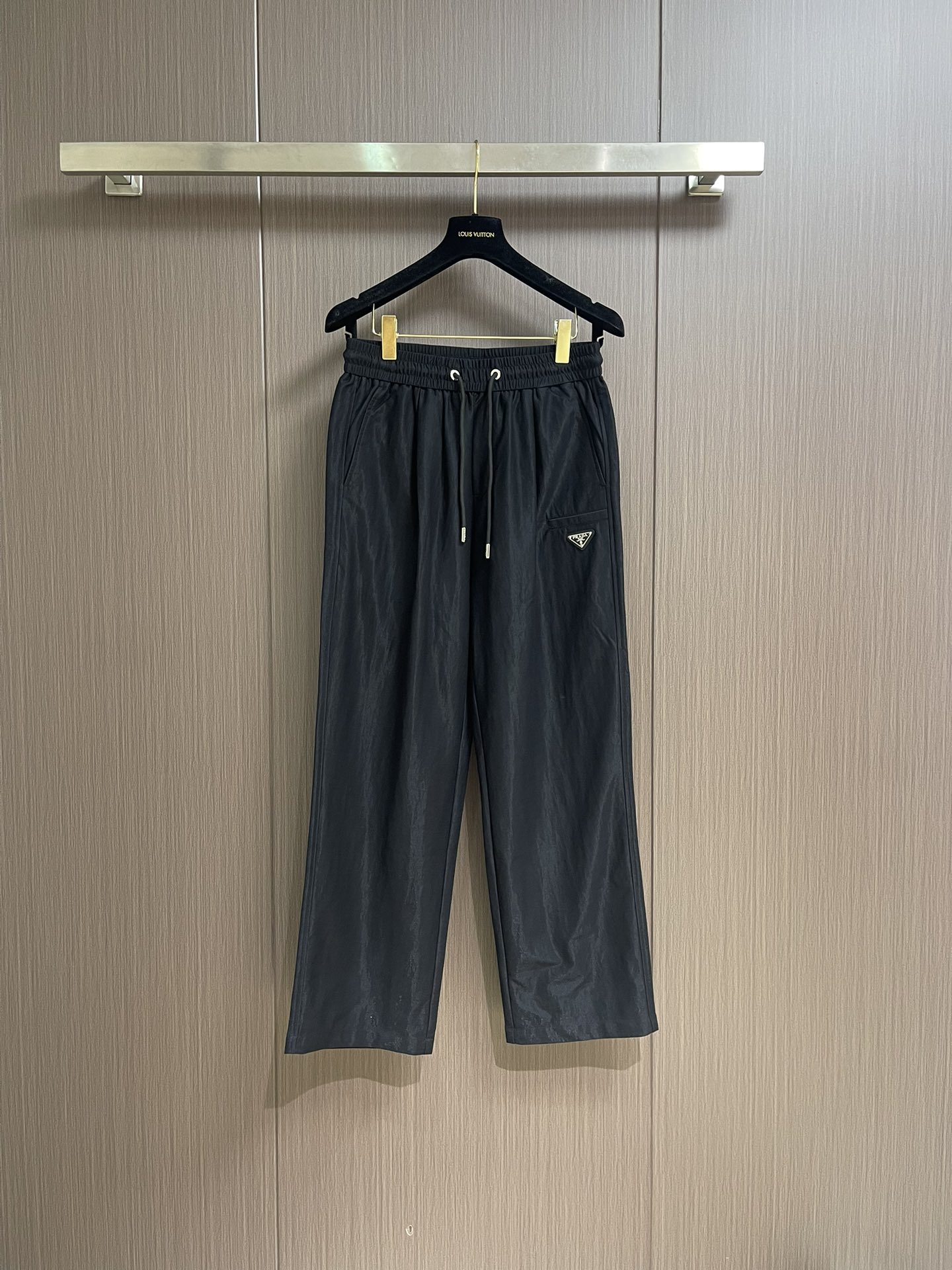 NO:473303,Prada Tencel Linen Elastic Waist Drawstring  Casual pants, on the fashionable and comfortable track, this Tiansi elephant waist drawstring casual pants are undoubtedly the well-deserved leader. It redefines the standards of high-end casual pants with exquisite craftsmanship and unique design. Selects Tiansi and linen blend fabrics to perfectly combine the smoothness of Tiansi and the texture of the sesame seeds. Tiansi fiber brings a silk-like delicate touch, gently sticking to the skin, as comfortable as the second layer of skin; the sesame seeds give the fabric natural texture and breathability, and can quickly expel moisture and keep the legs dry even in the stuffy season. This fabric combination is not only comfortable, but also has an excellent drape, making the pants naturally and smooth.  The waist is elegant. The design of elastic straps and drawstrings is a model of comfort and practicality. The high elastic elastic waist can perfectly fit all waistlines without being tight and easy to wear. The metal decorative head at the end of the drawstring is carefully polished and has a high gloss, which not only adds the exquisiteness of details, but also demonstrates the brand's ultimate pursuit of quality. The metal triangle logo on the front and rear pockets is a symbol of PR** identity. The logo is made of high-quality metal material and is finely polished to present a low-key and luxurious luster. Size XS-L, prada, alexander  wang19860909Prada 天丝亚麻松紧腰抽绳 休闲裤,在时尚与舒适的赛道上,这款天丝麻松紧腰抽绳休闲裤无疑是当之无愧的领跑者,它以精湛工艺与独特设计,重新定义高端休闲裤的标准.甄选天丝与麻混纺面料,将天丝的柔滑与麻料的质感完美融合.天丝纤维带来丝绸般的细腻触感,轻柔贴肤,如第二层肌肤般舒适；麻料则赋予面料天然的纹理与透气性,即使在闷热的季节,也能快速排出湿气,保持腿部干爽.这种面料组合不仅舒适,还具有出色的垂坠感,让裤型自然流畅,行走间尽显优雅.腰部采用松紧带与抽绳双结合的设计,堪称舒适与实用的典范.高弹性的松紧腰头能完美贴合各种腰围,不紧不勒,穿着自在.抽绳末端的金属饰头,经过精心打磨,光泽度高,不仅增加了细节的精致感,更彰显品牌对品质的极致追求.前侧口袋和后侧口袋上的金属三角徽标,是PR*＊身份的象征.徽标采用高品质金属材质,经过精细抛光处理,呈现出低调而奢华的光泽.尺码XS-L,,prada,alexander wang,Men's clothing