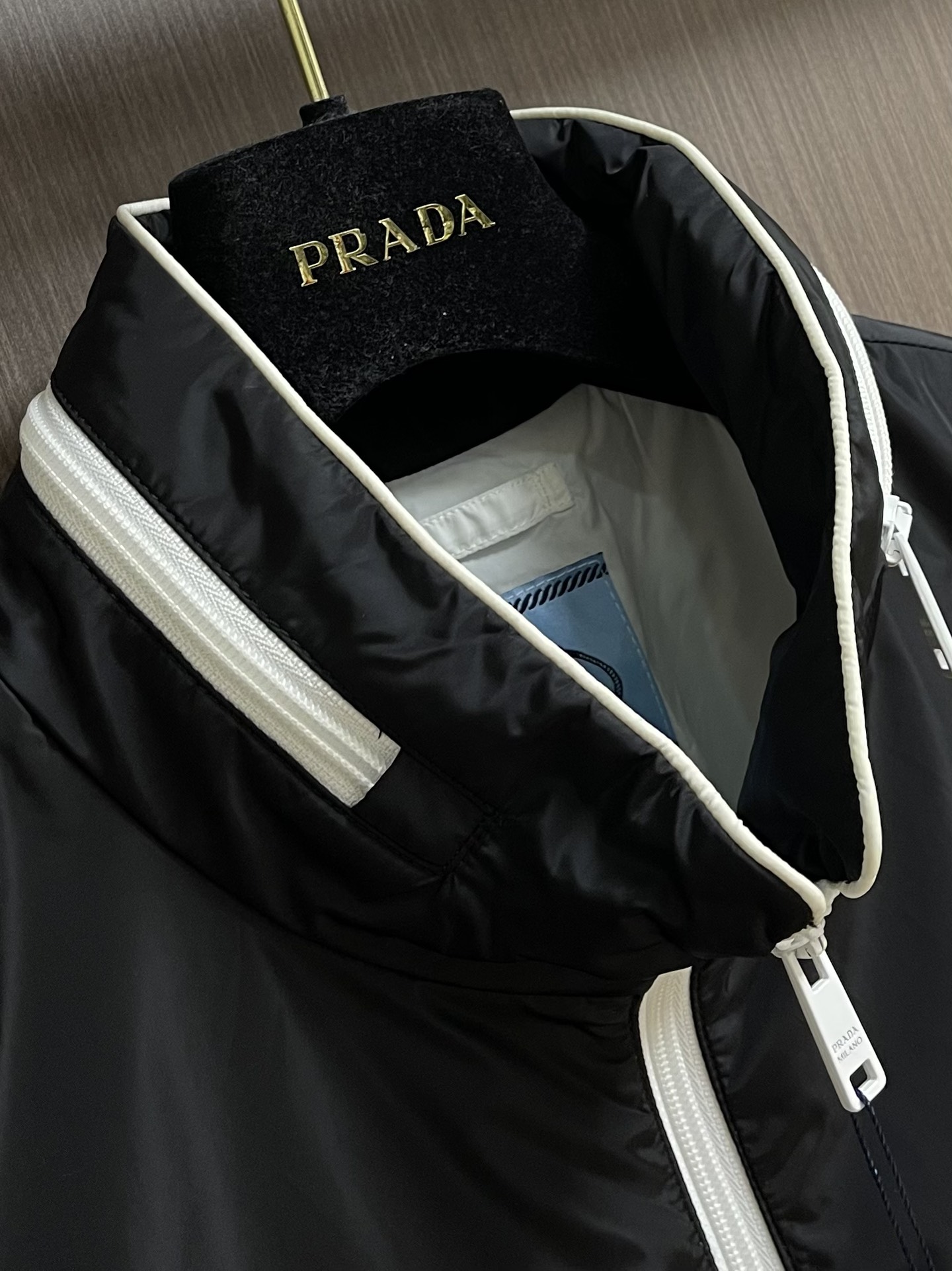 
PRADA 三角标再生尼龙外套，采用标志性的面料，是一种通过回收海洋中的塑料材料制成的再生尼龙织物体，