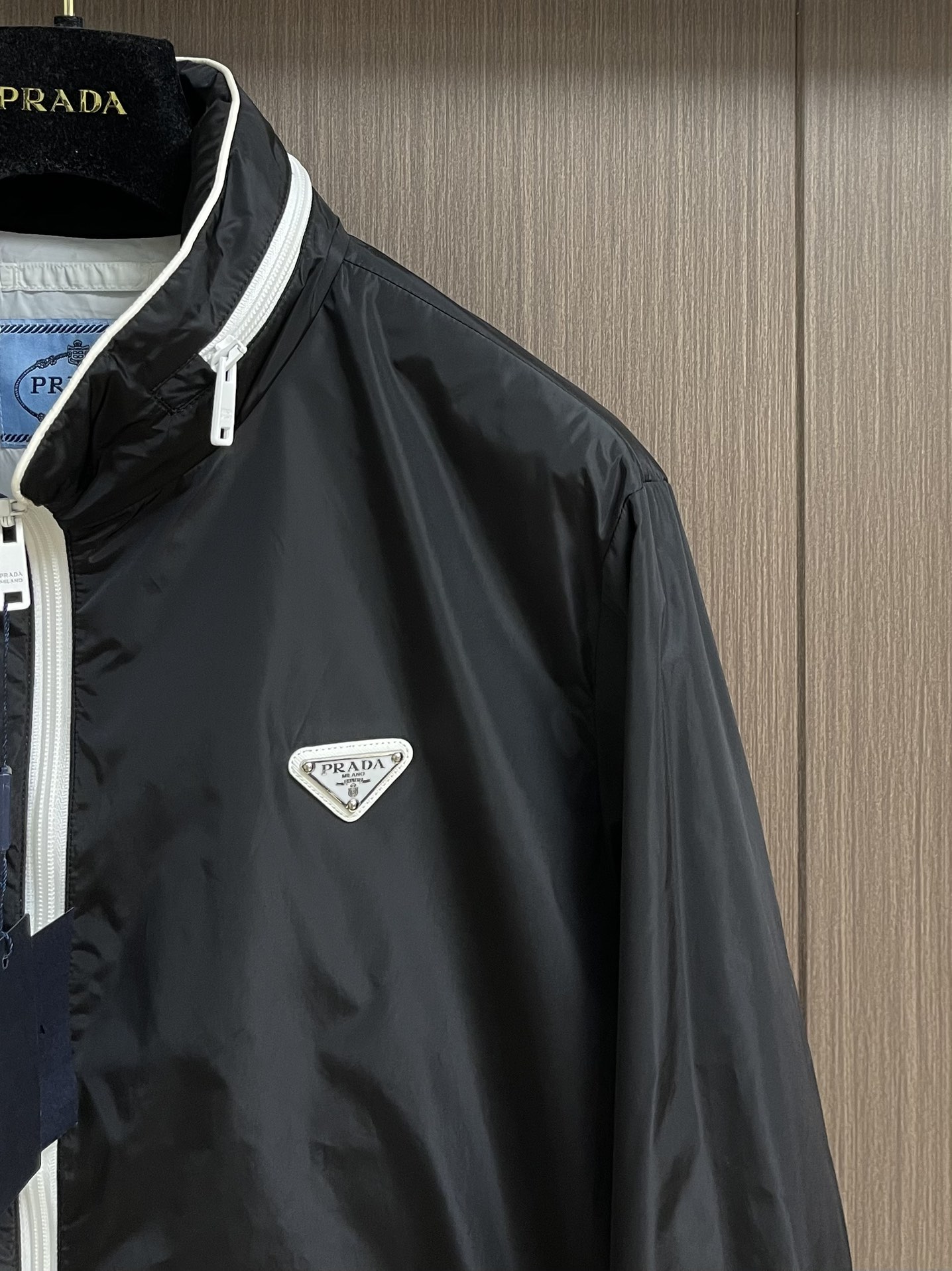 
PRADA 三角标再生尼龙外套，采用标志性的面料，是一种通过回收海洋中的塑料材料制成的再生尼龙织物体，