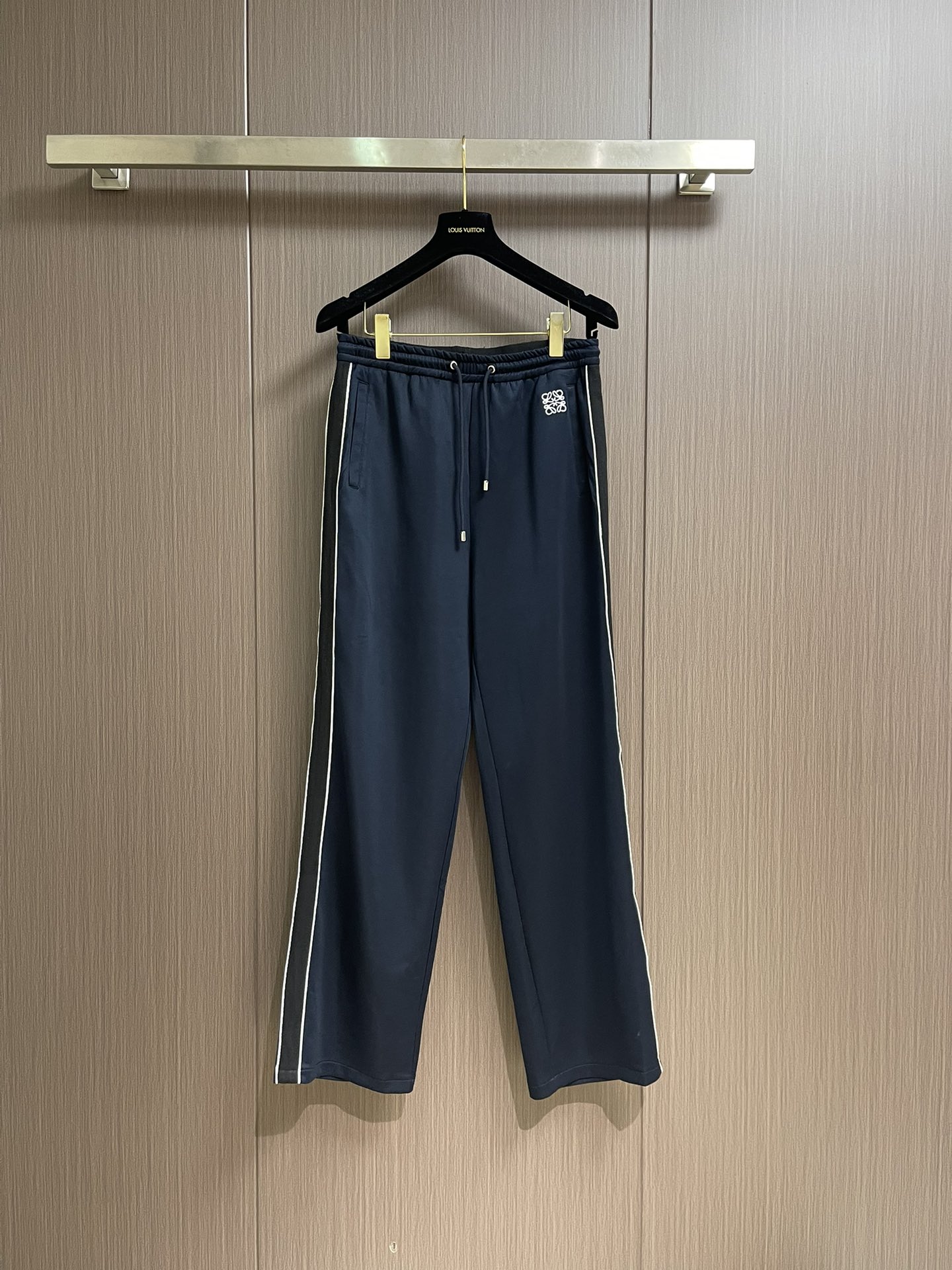 NO:515205,Loewe Contrast color webbing casual trousers, made of technological jersey knitted fabric, decorated with contrasting stripes and contrasting Anagram embroidery. The fabric consists of a sports material of polyester fiber. Before spinning, polyester fiber is fixed-dyeed dyed with imported environmentally friendly dyes, which has high strength and elastic recovery ability, so it is firm and durable, wrinkle-resistant and hot-resistant. The main body of the logo pattern uses white embroidery thread to create a precision needle embroidery process; the embroidery is very fine and dense. The embroidery thread is combined with encryption processing, and the embroidery body is It has a subtle matte visual texture. The embroidery surface is specially treated to make the silk thread smooth. Then, the overall embroidery pattern is finished with a flat embroidery needle method. The mid-waist vertical sports trousers style, the loose trousers are not limited to the figure and legs, and the inclusive vertical effect is significant. The waist and mid-waist trousers are decorated with a webbing design. The middle pleats and side pockets are connected to the trousers, and there are zippered oblique insertion pockets on both sides and back. The oblique insertion insertion insertion insertion insertion. Size XS-L,,loewe,alexander wang19860909Loewe 撞色织带休闲长裤,采用科技平纹针织面料,饰有对对比色条纹和对比色Anagram刺绣.面料由聚酯纤维的运动材质组成.聚酯纤维纺前采用进口环保材质染料定染加工,具有较高的强度与弹性恢复能力,因此牢固耐用、抗皱免烫.标识图案主体采用白色绣线打造精密挨针绣工艺；刺绣非常精细针法绵密.采用亚麻材质绣线结合加密处理,绣体具有微妙的哑光视觉质感.刺绣表面进行特殊处理,使丝线平整顺滑,接着利用平绣的针法,进行整体刺绣图案收尾.中腰垂直款运动长裤版型,宽松裤管不限身材与腿型,包容性强垂直效果显著.连腰中腰裤管两侧饰有人字织带设计.连接裤中褶与侧兜,两侧及后幅有拉链斜插袋,斜插式插手置物.尺码XS-L,,loewe,alexander wang,Men's clothing