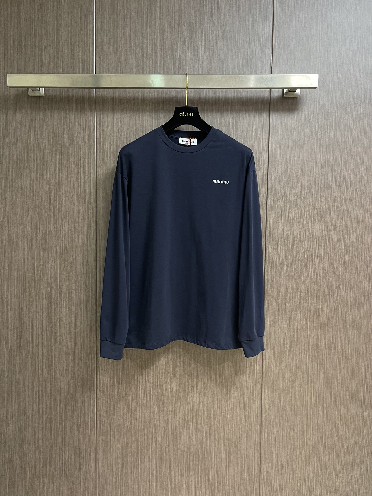 NO:528030,MIUMIU 2025SS round neck navy blue long-sleeved T-shirt, using high-grade 24 combed cotton yarns, ensuring color uniformity through the 'dyeing first and then weaving' process. The yarn is twisted by double strands to improve pill resistance, and the finish of the cloth is better than that of ordinary cotton fabrics. The 190g weight of the plate is precisely controlled by 18-needle fine needle-drawing round machine, taking into account the drape and clarity. It is necessary to cooperate with a constant temperature and humidity workshop to avoid yarn tension fluctuations. The compact spinning structure  Learning from Swiss Rider tight spinning technology, the yarn hair is reduced by 60, and the fabric density is 156 stitches in 2, achieving the touch of the baby's skin while maintaining an elastic recovery rate of more than 8%. The Japanese FIL-TEC embroidery special polyester thread is used to use imported Tajima machine equipment to ensure that there is no burrs on the edges of the high-density embroidery pattern of 12 stitches per inch. The bottom layer is first positioned with a water-soluble lining, the middle layer is filled with the tiny silk pad yarn, the surface layer is made of the carving and embroidery process to create an air-sensitive three-dimensional effect, and the breathability of the embroidery parts remains above 65CFM. Size 48-56,,miumiu,tees,t-shirt,alexander wang19860909MIUMIU 2025SS圆领藏青色长袖T恤,采用高品级24支精梳棉纱线,通过「先染后织」工艺确保色彩均匀性,纱线经双股加捻提升抗起球性,布面光洁度优于普通棉织物. 对版190克重精密调控通过18针细针距圆机编织,兼顾垂坠感与挺括性,需配合恒温恒湿车间避免纱线张力波动.紧密纺结构 借鉴瑞士立达紧密纺技术,纱线毛羽减少60,织物密度达156针英寸2,实现婴儿肌肤触感的同时保持8％以上的弹性回复率,采用日本FIL-TEC刺绣专用涤纶线,实用进口田岛机设备,确保每英寸12针的高密度刺绣图案边缘无毛刺.底层先以水溶衬定位,中层填充天丝垫纱,表层以雕孔绣工艺打造空气感立体效果,刺绣部位透气性仍保持65CFM以上.尺码48-56,,miumiu,tees，t-shirt,alexander wang,Men's clothing