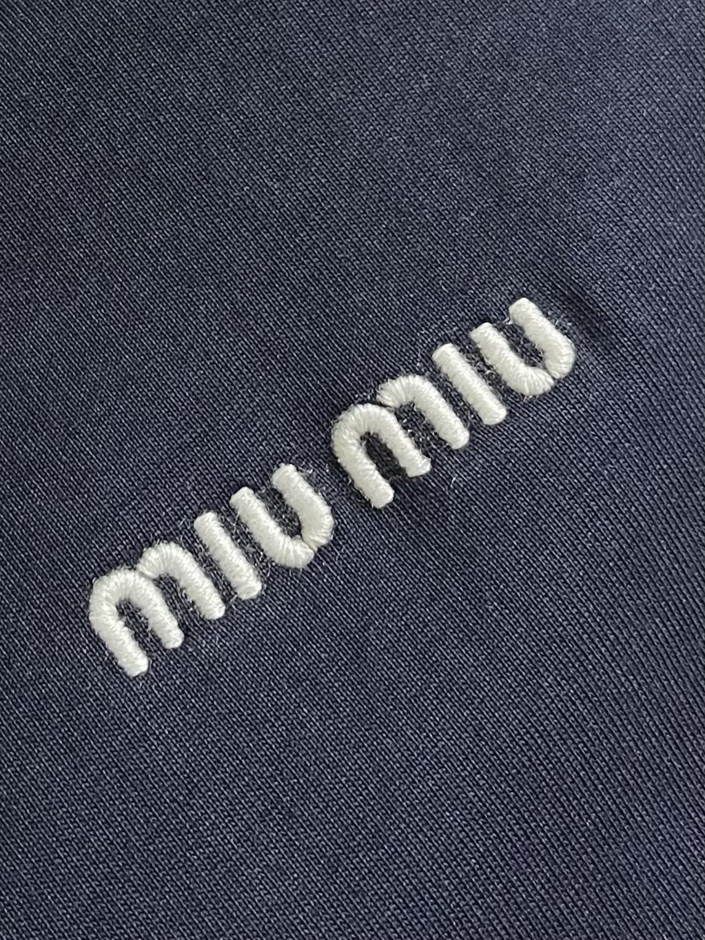 MIUMIU 2025SS圆领藏青色长袖T恤，采用高品级24支精梳棉纱线，通过「先染后织」工艺确保色彩均