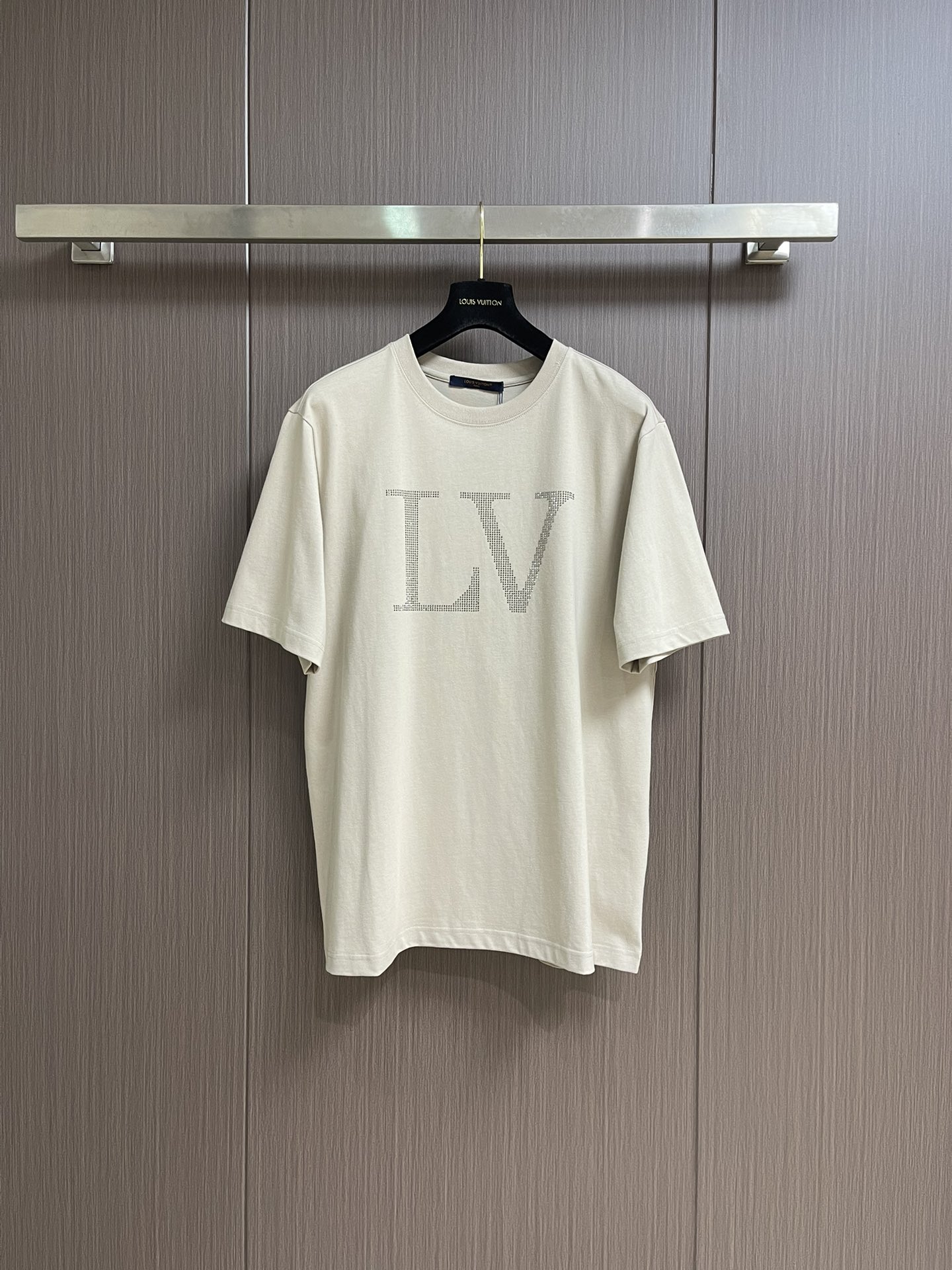 NO:523665,LV 2025SS early autumn new rhinestone letter short-sleeved T-shirt. When the classic logo encounters bright rhinestones, this V short-sleeved V-sleeved unlocks new paradigms for you.  The LV letters on the chest are made of countless exquisite rhinestones, which reflect the sparkling luster under the light, which makes you come in the crowd and easily become the visual center. 99% cotton-blend fabric is soft and skin-friendly and draped, and is comfortable and casual in daily wear; delicate stitching and exquisite tailoring, from shoulder lines to hem, every detail shows luxury ingenuity, and the texture is visible to the naked eye. Simple beige tones are suitable for various dressing scenes, and can be matched with denim to create a casual and trendy style, and can also mix and match with suits to create a high-end feel. Oversize style is friendly to the body, whether it is street or light luxury social interaction, it can help you interpret a unique fashion attitude. Size XS-L,,louis vuitton, versace, T-shirt,tees, t-shirt, business  suit,alexander wang19860909LV 2025SS早秋新款水钻字母短袖T恤,当经典标识邂逅璀璨水钻,这款V短袖为你解锁奢潮新范式. 胸前超大尺寸的LV字母,由无数颗精致水钻密镶而成,在光线下折射出粼粼光泽,将品牌辨识度拉满的同时,让你在人群中自带,轻松成为视觉中心.99％棉混纺面料,柔软亲肤且兼具垂坠感,日常穿着舒适随性；细腻的缝线工艺与考究的剪裁,从肩线到衣摆,每一处细节都彰显奢品匠心,质感肉眼可见.简约米色调适配各种穿搭场景,可搭配牛仔打造随性潮范,也能与西装混搭出高级感,oversize版型对身形友好,无论是街头出街还是轻奢社交,都能助你演绎独树一帜的时尚态度.尺码XS-L,,louis vuitton,versace,T-shirt,tees，t-shirt,business suit,alexander wang,Men's clothing