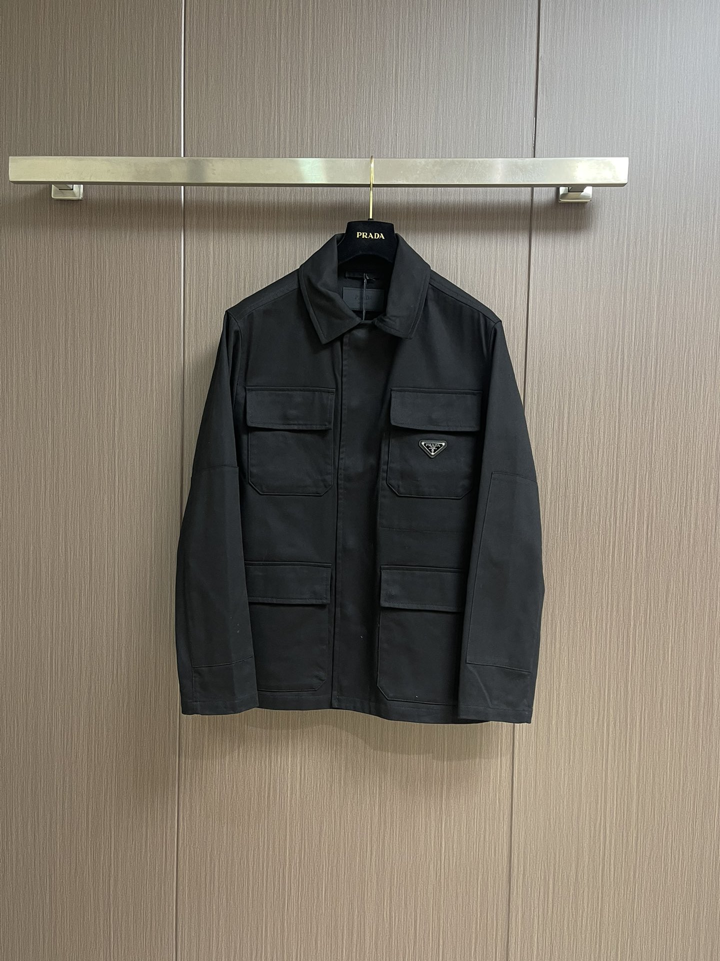 NO:524773,PRADA  The cotton workwear style jacket uses 45° oblique warp and weft to construct the fabric muscles and bones. The tightly arranged cotton yarns form a natural three-dimensional texture, giving them a practical base that is anti-wrinkle and wear-resistant. At the same time, the matte texture echoes the rough aesthetics of the workwear style. It retains the natural skin-friendly and sweat-absorbing ability of the cotton fibers, while taking into account both warmth and breathability. The natural stiffness of the fabric is used to reinforce the shoulder joints through double-layer cotton yarn to create a sculptural wide shoulder profile to avoid soft collapse and deformation. The cuffs are embedded with invisible thread lining to ensure freedom in every move. Through low-temperature ironing and oblique  The natural hardness of the pattern fabric is integrated to create a 30-degree bracing angle, so that the neckline fits the neck curve and improves wear comfort. Abandon traditional lining, shape the silhouette with the crispness of the fabric itself, reducing redundant layers while improving breathability. The hidden button closure and flat bottom edge design enhance the tough temperament and loose fit to avoid bloating. The symmetrical flip patch pocket enhances practicality, and the three-dimensional silhouette adds a sense of layering. The tight stitching at the edges makes the bag solid while adding beauty. Size S-XL, prada, jackets  & coats,alexander wang19860909PRADA 棉质工装风夹克,以45°斜向经纬交织构筑面料筋骨,紧密排列的棉纱形成天然立体肌理,赋予抗皱耐磨的实用基底,同时通过哑光质感呼应工装风的粗粝美学,其保留了棉纤维天然的亲肤性和吸汗能力,同时又兼顾保暖性和透气性.利用面料天然硬挺性,通过双层棉纱加固肩线接缝,打造雕塑感宽肩轮廓,避免软塌变形.袖口内嵌隐形螺纹衬条,确保举手投足间的自如.通过低温压烫与斜纹布自然的硬度融合,打造30度力挺角度,使领口贴合颈部曲线,提升穿着舒适度.摒弃传统衬里,以面料本身的挺括度塑造廓形,减少冗余层次的同时提升透气性.隐藏式纽扣开合和平直底边设计强化硬朗气质与宽松版型形成平衡,避免臃肿感.对称翻盖贴袋强化实用性,立体廓形增添层次感.边缘处紧密的缝线使袋体牢固的同时又增添美感.尺码S-XL,,prada,jackets & coats,alexander wang,Men's clothing