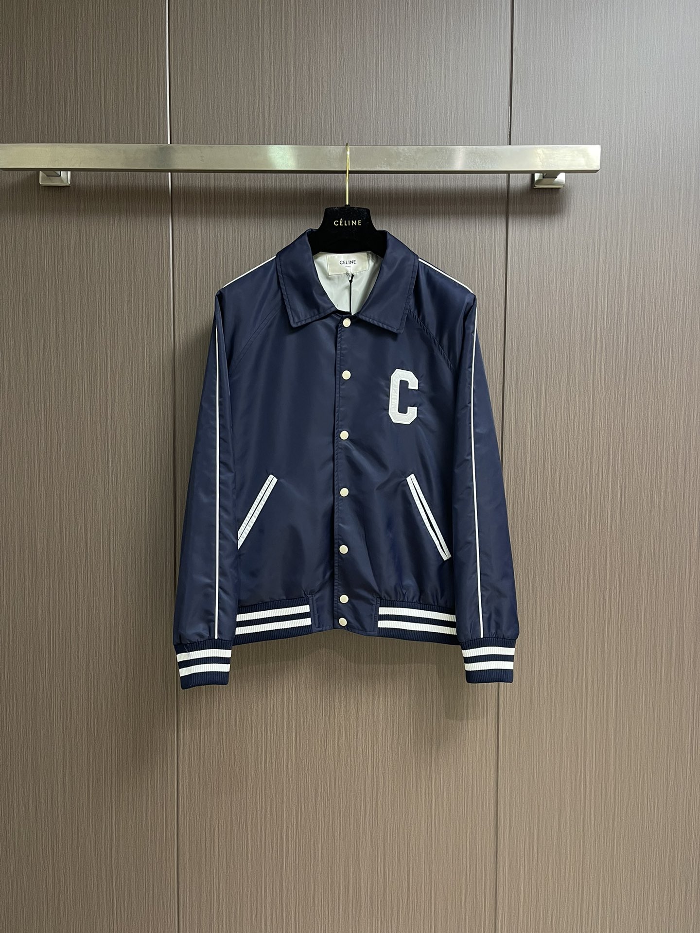 NO:531261,Celine  2025FW early autumn new college-style baseball uniform, the giant white 'C' letter embroidery on the front chest and the three-dimensional embroidery on the back, are created with exclusive brand craftsmanship, with precise stitching and three-dimensional sense. Against the backdrop of the navy blue satin nylon fabric, it not only releases the vitality and tension of the American Academy, but also highlights the exquisite style of the French luxury brand; the metal engraving quad buckles are clear brand letter logos conveying the brand texture from the opening and closing; the contrasting stripes ribs on the hem and cuffs are classic elements of the college style, and at the same time, the crisp style of the clothes is strengthened, allowing the retro trend to be filled with details. The blue satin nylon fabric is made of silky touch and crisp draping, which is not easy to wrinkle and easy to handle in daily wear.  ; The fine edge locking and sewing craftsmanship inside continues the brand's strict quality requirements, making this baseball uniform not only a piece of clothing, but also a fashionable artwork that can be collected for a long time. The loose style of the same style of men and women is suitable for a variety of figures and styles. It can be paired with a white T-shirt inside to create a street style; it can also be layered with a pleated skirt to interpret the sweet and cool feeling of the college; even with suit pants, it can collide with a unique accent of 'elegant luxury'. From campus commuting to urban outings, to light luxury socializing, it uses the attribute of 'unbounded style' to help you become a fashion protagonist with a retro and high-end feel in every occasion. Size S-XL, celine, skirts, business  suit,alexander wang19860909Celine 2025FW早秋新品学院风棒球服,前胸的巨型白色'C'字母刺绣与后背的品牌字母立体绣花,采用品牌独家工艺打造,针脚精密且富有立体感,在藏蓝色缎面锦纶面料的衬托下,既释放美式学院的活力张力,又彰显法式奢牌的精致格调；金属刻字四合扣上清晰的品牌字母标识,从开合间传递品牌质感；下摆与袖口的撞色条纹罗纹,学院风经典元素,同时强化衣物的挺括版型,让复古潮范在细节处拉满.选用蓝色缎面锦纶面料,兼具丝滑触感与挺括垂坠感,日常穿着不易起皱且便于打理；内里的精细锁边与车缝工艺,延续品牌对品质的严苛要求,让这件棒球服不仅是穿搭单品,更是可长久收藏的时尚艺术品.男女同款的宽松版型,适配多元身形与风格.可内搭白T配,打造街头潮酷风；也能叠穿配百褶裙,演绎学院甜飒感；甚至搭配西装裤,都能碰撞出'雅痞奢潮'的独特腔调.从校园通勤到都市出街,再到轻奢社交,它以'风格无界'的属性,助你在每一个场合都成为兼具复古感与高级感的时尚主角.尺码S-XL,,celine,skirts,business suit,alexander wang,Men's clothing