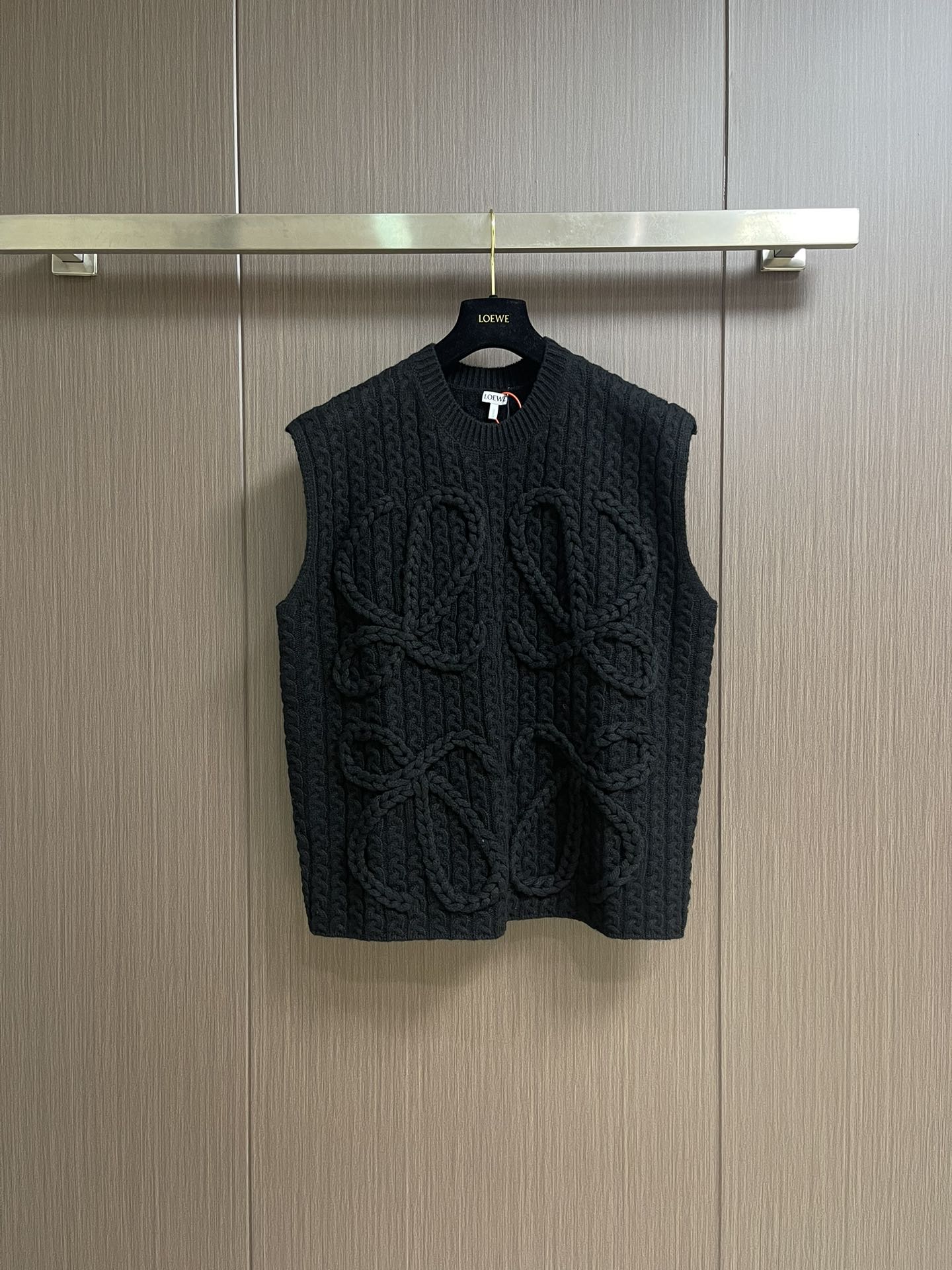 NO:530147,Loewe Anagram Twist knitted sleeveless vest sweater, fixed knit heavy mercerated wool embossed knitted wool material, full texture, heavy and solid, with black as the background, hand-cranked special machine relief pattern technology, customized special knitting machine by hand man-machine collaborative knitting logic, real-time adjustment of yarn tension to control the rise and fall of knitting needles, forming Loewe Anagram flower pattern with three-dimensional concave and convex texture, full-region twist rope composite double process, symphonic weaving of hand and machinery, the whole piece of clothing uses twist rope + webbing composite weaving, line by line, manual connection, 3 steps to wrap twist ropes and insert, one webbing, and one stitch to reset the bed. It takes a total of 200-300 rows (time and effort consuming)  Expensive) Size S-XL, loewe, loewe, sweaters, alexander wang19860909Loewe 罗意威 Anagram 麻花编织无袖马甲毛衣,定织重磅丝光羊毛浮雕针织毛料 质感十足 厚重扎实 以玄黑为底色 手摇专机浮雕花型工艺 通过匠人手工操控定制化专用编织机 人机协同的编织逻辑 实时调整纱线张力控制织针起落 形成具有立体凹凸肌理的Loewe Anagram花型图案 全域扭绳复合双工艺 手工与机械的交响织艺 整件服饰均采用扭绳＋织带复合编织 逐行手工衔接 每编织1行需完成扭绳缠绕一织带穿插一针床复位3个步骤 编织一件成衣需累计200-300行（耗时耗力 工价昂贵）尺码S-XL,,loewe,loewe,sweaters,alexander wang,Men's clothing