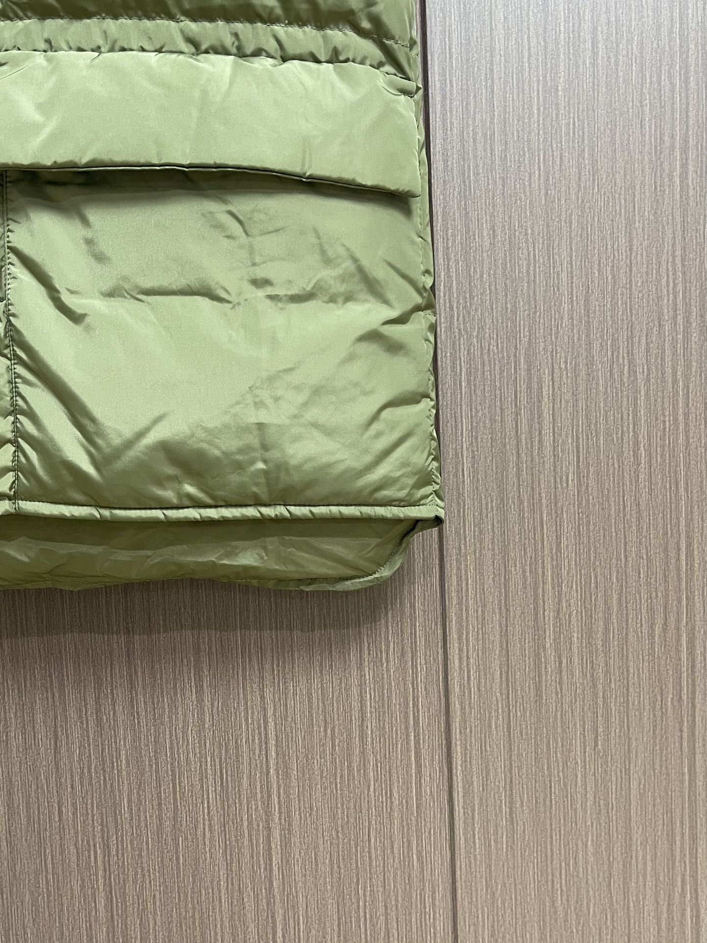 Prada 饰织物三角标羽绒马甲，选品牌标志性的再生尼龙面料，与传统尼龙性能相当，具备高强度，抗撕裂，耐