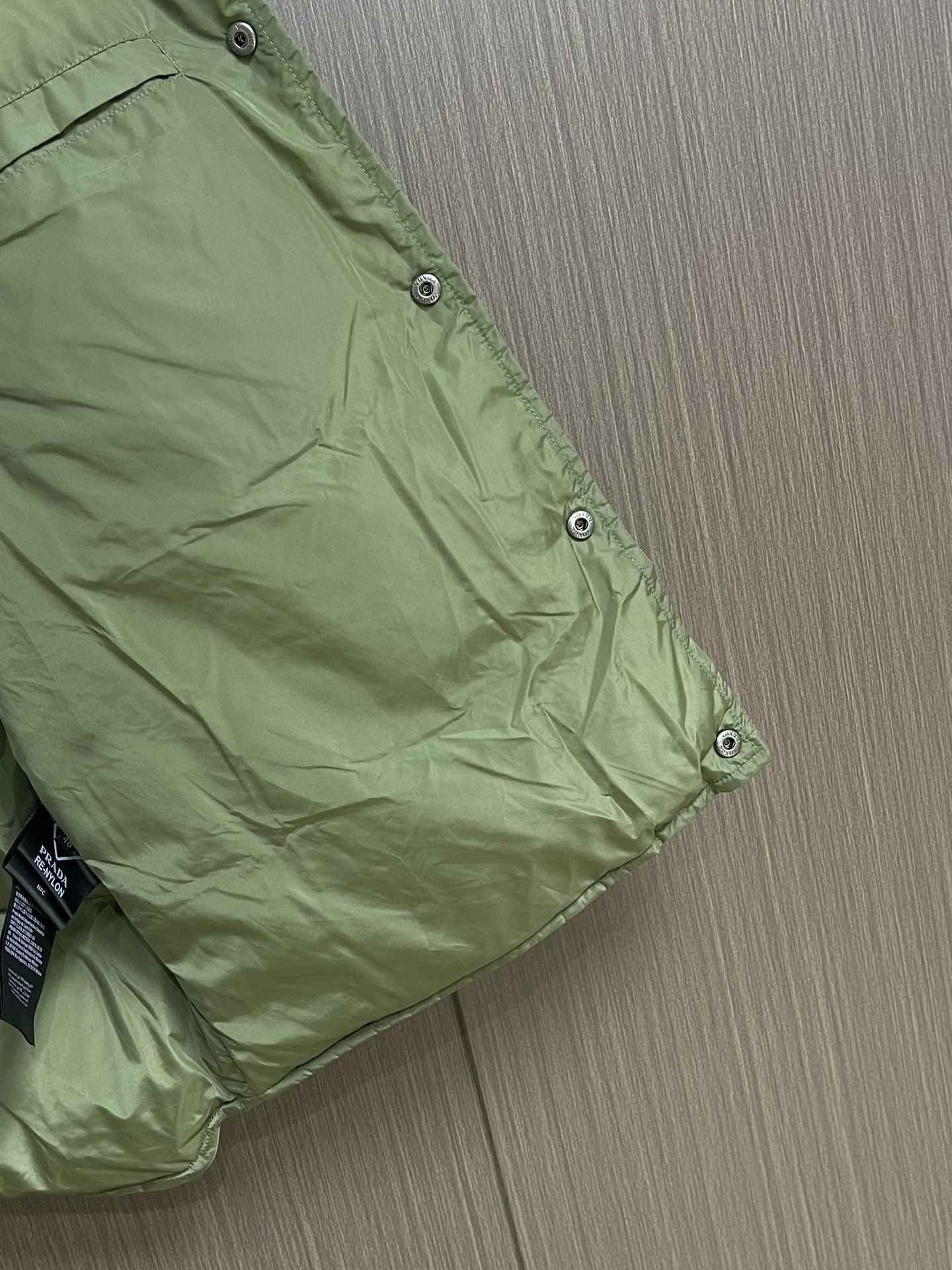 Prada 饰织物三角标羽绒马甲，选品牌标志性的再生尼龙面料，与传统尼龙性能相当，具备高强度，抗撕裂，耐