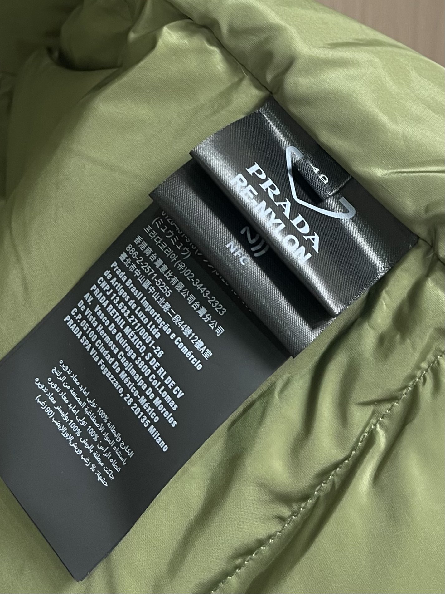 Prada 饰织物三角标羽绒马甲，选品牌标志性的再生尼龙面料，与传统尼龙性能相当，具备高强度，抗撕裂，耐