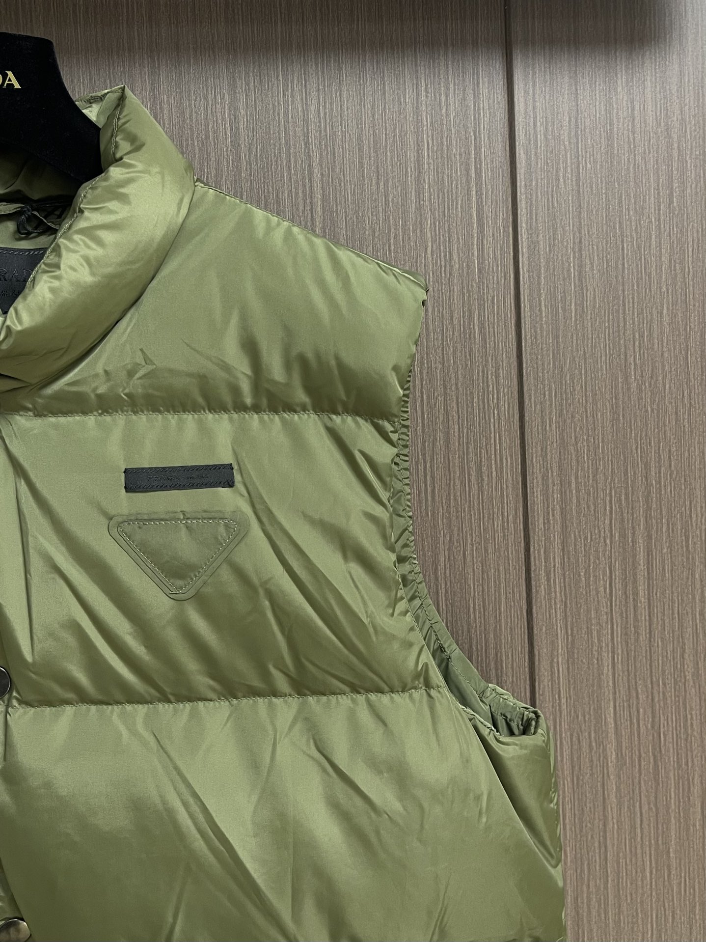 Prada 饰织物三角标羽绒马甲，选品牌标志性的再生尼龙面料，与传统尼龙性能相当，具备高强度，抗撕裂，耐