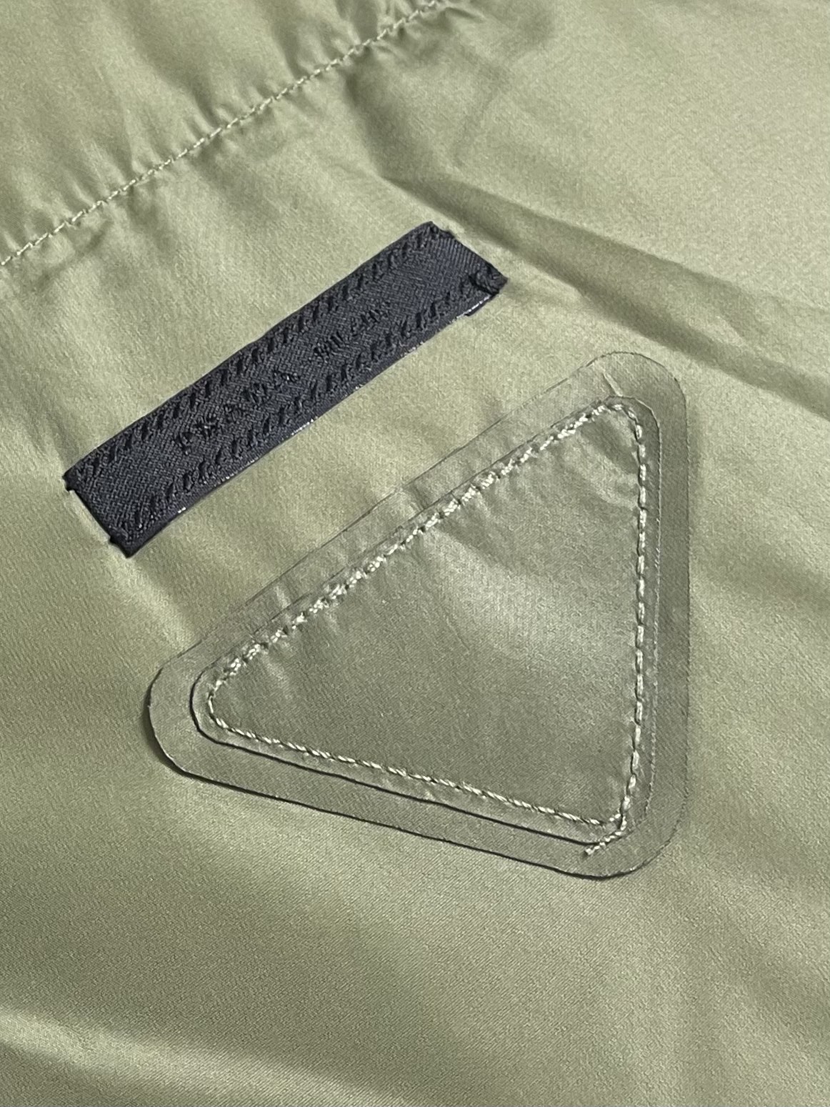 Prada 饰织物三角标羽绒马甲，选品牌标志性的再生尼龙面料，与传统尼龙性能相当，具备高强度，抗撕裂，耐