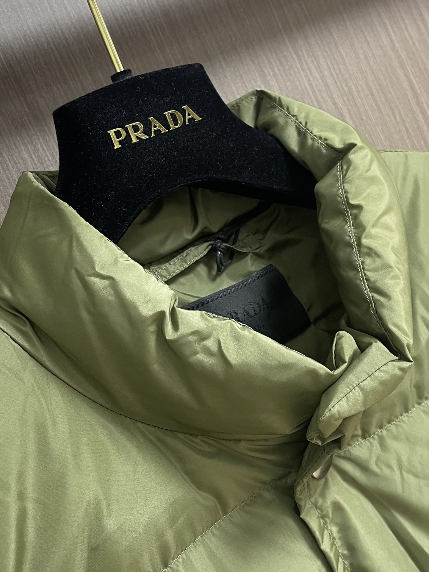 Prada 饰织物三角标羽绒马甲，选品牌标志性的再生尼龙面料，与传统尼龙性能相当，具备高强度，抗撕裂，耐