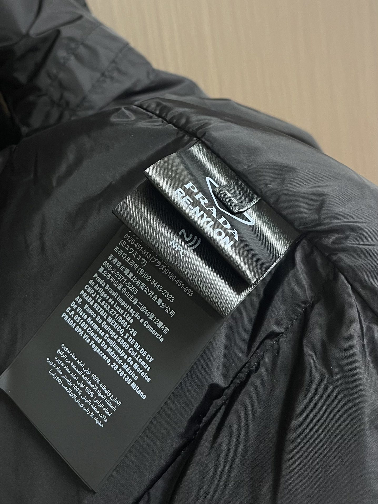 Prada 饰织物三角标羽绒马甲，选品牌标志性的再生尼龙面料，与传统尼龙性能相当，具备高强度，抗撕裂，耐