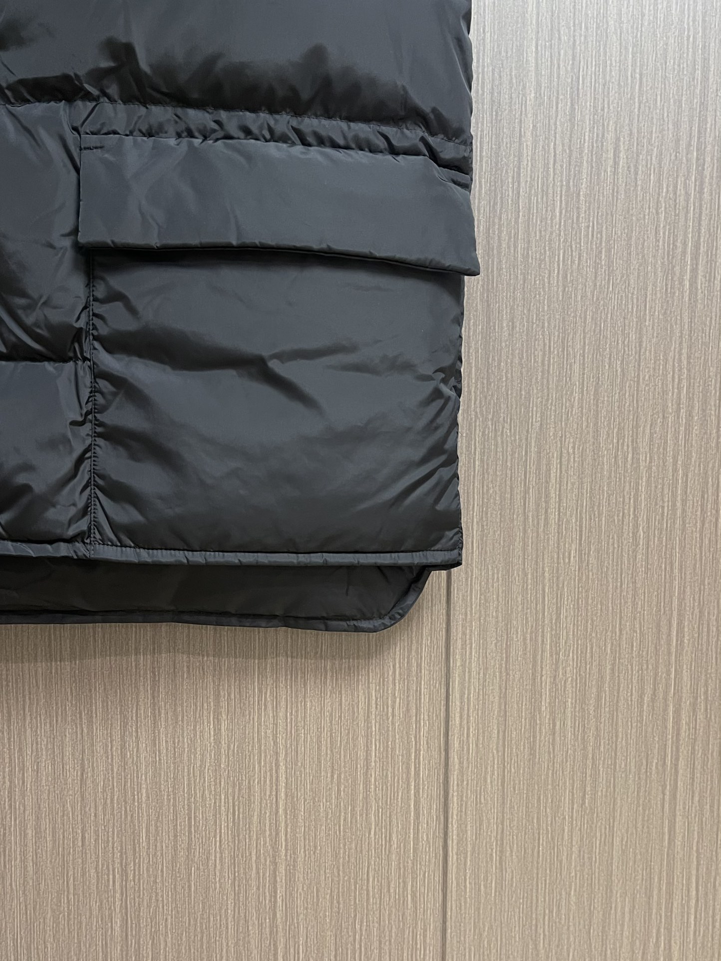 Prada 饰织物三角标羽绒马甲，选品牌标志性的再生尼龙面料，与传统尼龙性能相当，具备高强度，抗撕裂，耐