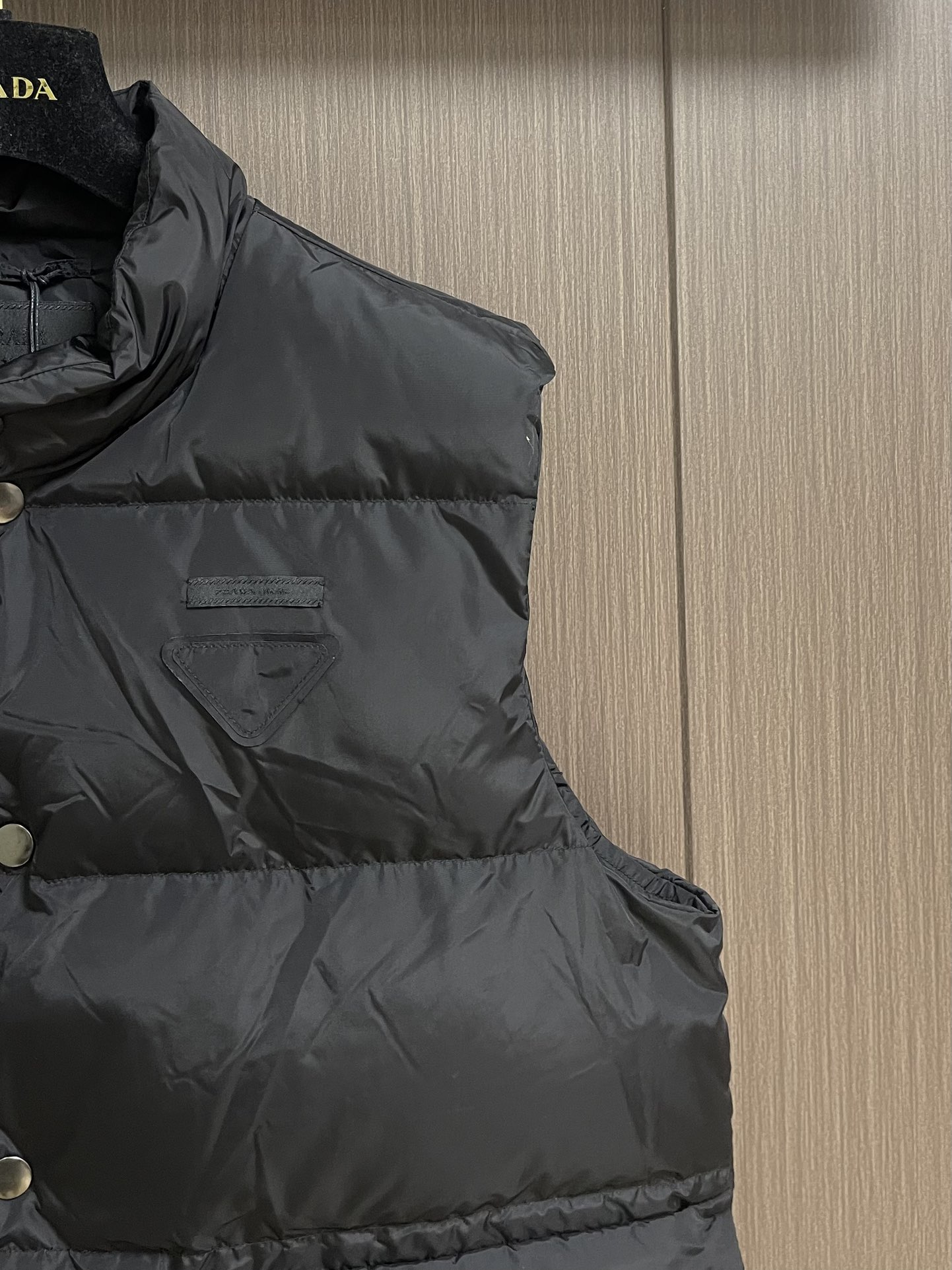 Prada 饰织物三角标羽绒马甲，选品牌标志性的再生尼龙面料，与传统尼龙性能相当，具备高强度，抗撕裂，耐