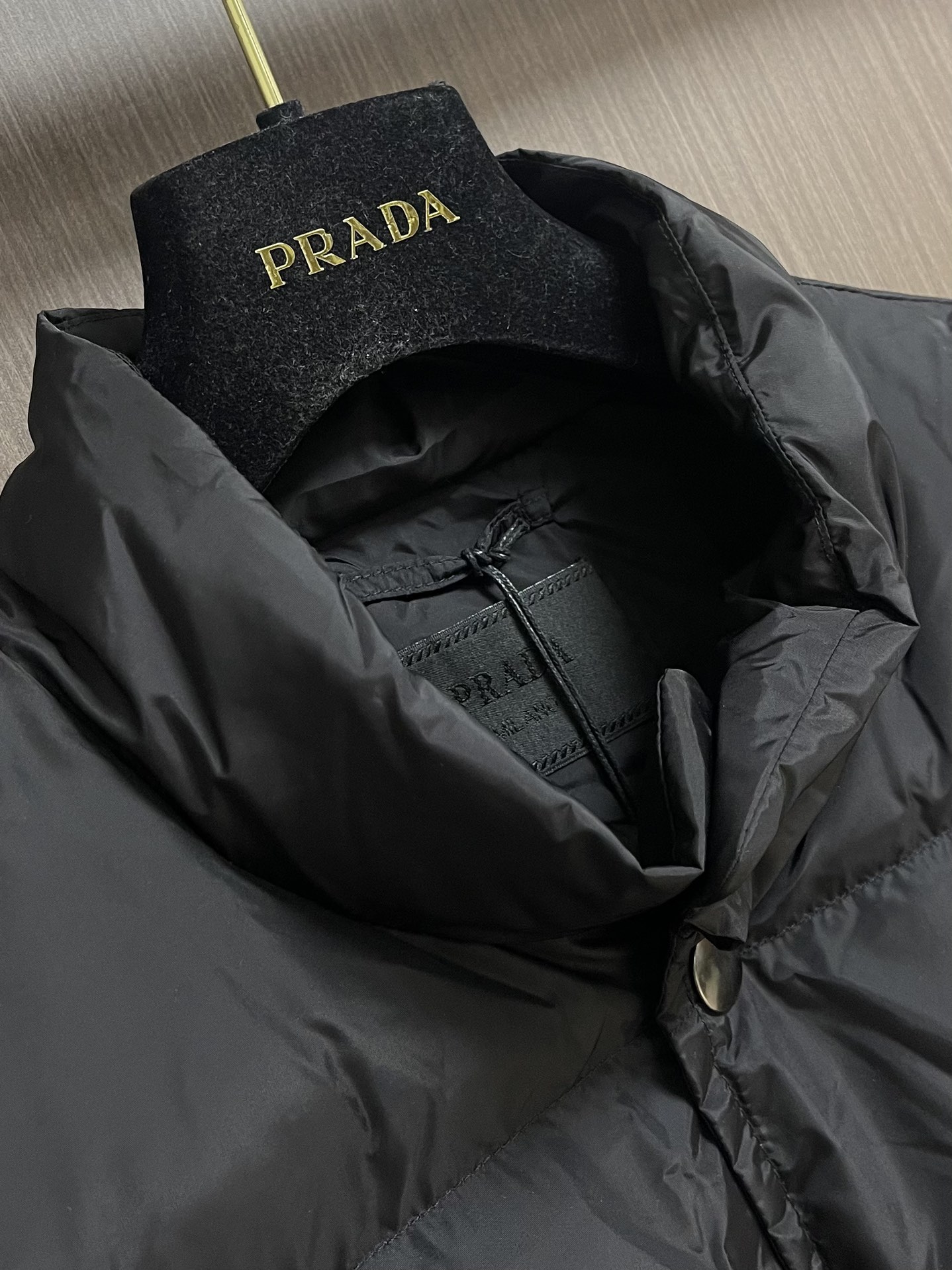 Prada 饰织物三角标羽绒马甲，选品牌标志性的再生尼龙面料，与传统尼龙性能相当，具备高强度，抗撕裂，耐