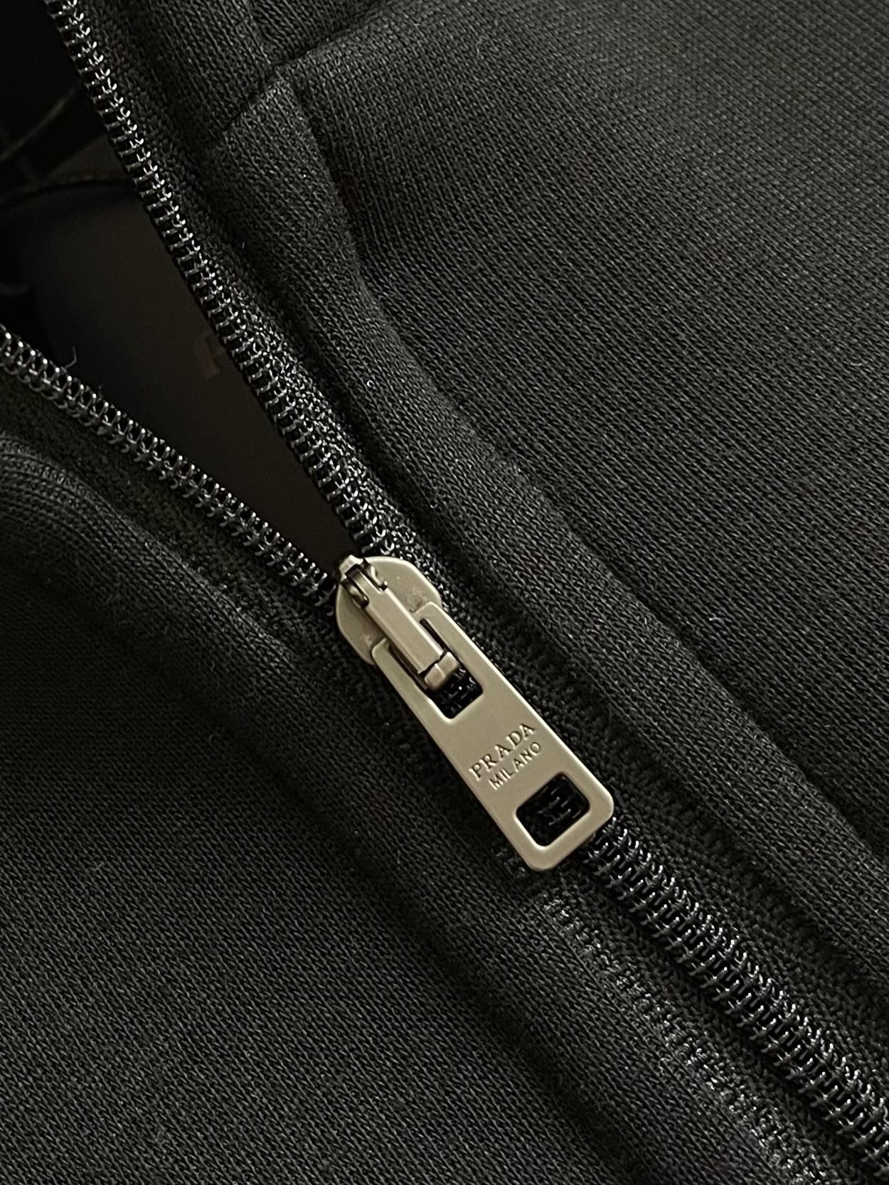 Prada 尼龙丝光拼接罗马面料拉链外套，采用380克丝光双面，该款面料偏柔软，密度高，高密度面料可有效