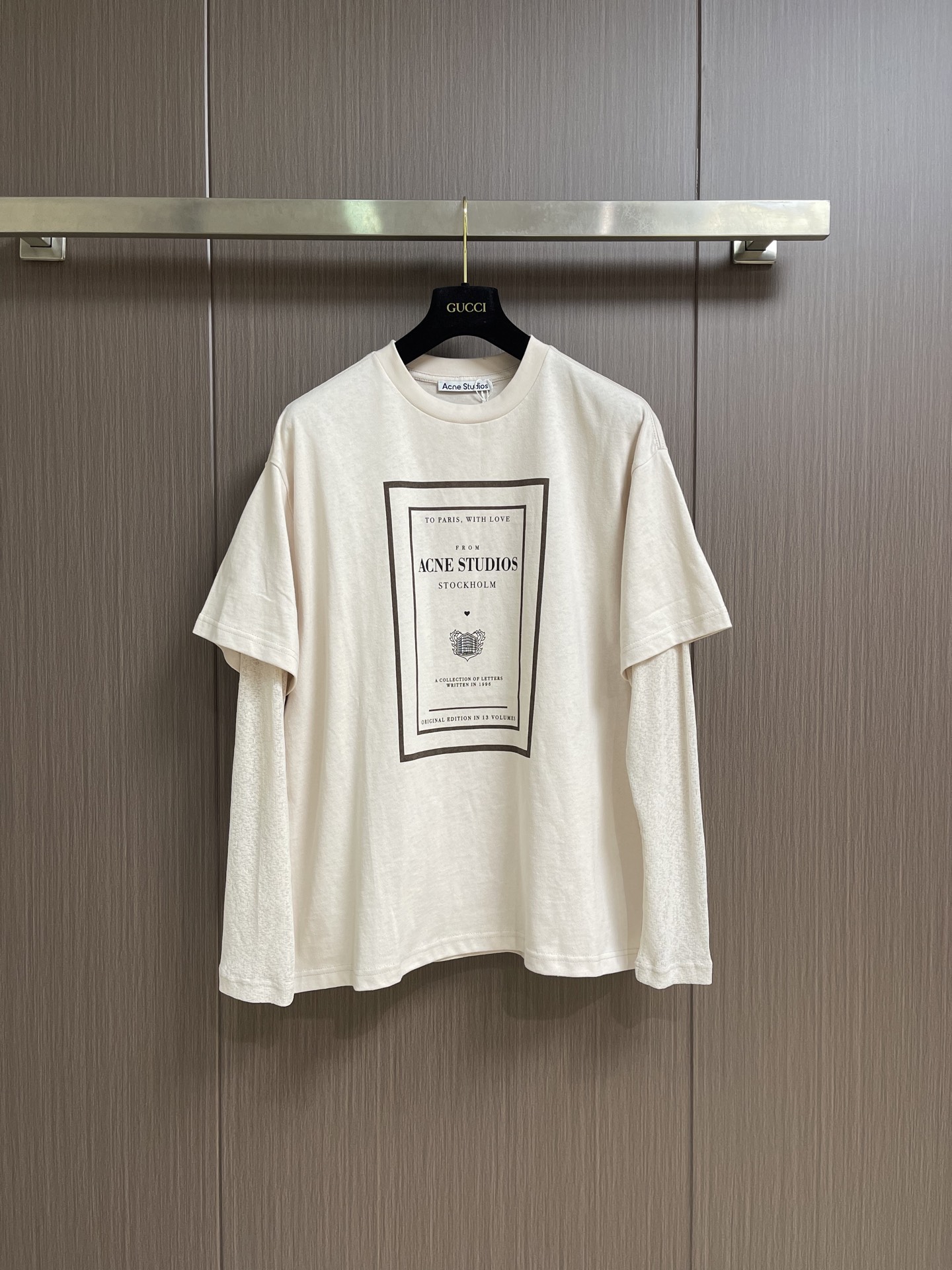 NO:836115,Acne Studios  There are two fake long-sleeved T-shirts in the collection of letters. The main fabric is 12-count fine cotton plain weave, 230gm; the ribbing uses 32-count double yarn, 350gm. 12-count is a coarse yarn count, which means that the yarn is thicker and has a lower twist. After being woven into plain weave, it will form an obvious slub feel or irregular texture. This kind of fabric  Abandoning the smoothness and delicacy of combed cotton, it deliberately retains a dry feel and slightly loose structure similar to a vintage distressed T-shirt. The weight of the fabric ensures that this rough texture will not collapse and can independently support a loose silhouette. The upper body will have a crisp paper feel and excellent breathability. The sleeves are made of polyester ribbing. Thorough use is used here  The heterogeneous splicing body is made of soft pure cotton, but the sleeves are made of functional chemical fiber. The polyester rib has natural elastic recovery and drape, which allows the sleeve shape to rebound quickly even after strenuous activities, without causing the bulging that is easy to occur in cotton cuffs. The seasonal pattern on the front chest uses a penetration printing process, through special additives and high-quality  Under high temperature and high pressure conditions, the dye molecules are completely dissolved and penetrated into the interior of the cotton fiber, and are covalently bonded with the fiber. For fabrics with uneven surface texture such as 12-count roving, penetration printing shows great advantages, and is evenly distributed along the fiber texture. The overall wiring is straight and delicate, the fabric is comfortable and soft, and the color is consistent without color difference.  It can be matched with the same style to create a fashionable look, and can be used in various occasions. Customized accessories, complete with three standards, same style for men and women!  Sizes XS-L19860909Acne Studios 信件合集假两件长袖T恤,主身面料选用的是12支精棉平纹,230gm；搭配罗纹采用了32支双纱,350gm.12支属于粗纱支,这意味着纱线较粗且捻度较低,织成平纹布后会形成明显的竹节感或不规则肌理.这种面料放弃了精梳棉的光滑细腻,刻意保留了一种类似复古做旧T恤的干爽手感和微疏松结构.面料克重确保了这种粗犷肌理不会垮塌,能独立支撑起宽松的廓形,上身会有一种挺括的纸张感,透气性极佳.衣袖采用了涤纶罗纹.这里运用了彻底的异质拼接衣身是柔软的纯棉,袖子却是功能性化纤.涤纶罗纹具有天然的弹性恢复能力和垂坠感,这使得袖型即使经过剧烈活动也能迅速回弹,不产生棉质袖口易出现的鼓包.前胸的当季图案采用了渗透印花工艺,通过特殊的助剂和高温高压条件,使染料分子完全溶解并渗入棉纤维的内部,与纤维发生共价键结合.对于12支粗纱这种表面肌理凹凸不平的面料,渗透印花展现了极大的优势,顺着纤维纹理均匀分布.整体走线平直细腻,面料舒适柔软,颜色一致无色差 能与同款搭配营造时尚造型,驾驭各种场合,定制辅料,三标齐全,男女同款！尺码XS-L XS码胸围120肩宽53衣长71.5 S码 胸围124肩宽54.5 衣长73.5 M码胸围128肩宽56 衣长75.5 L码 胸围132肩宽57.5 衣长77.5,,acne studios,dior,tees，t-shirt,,Men's clothing