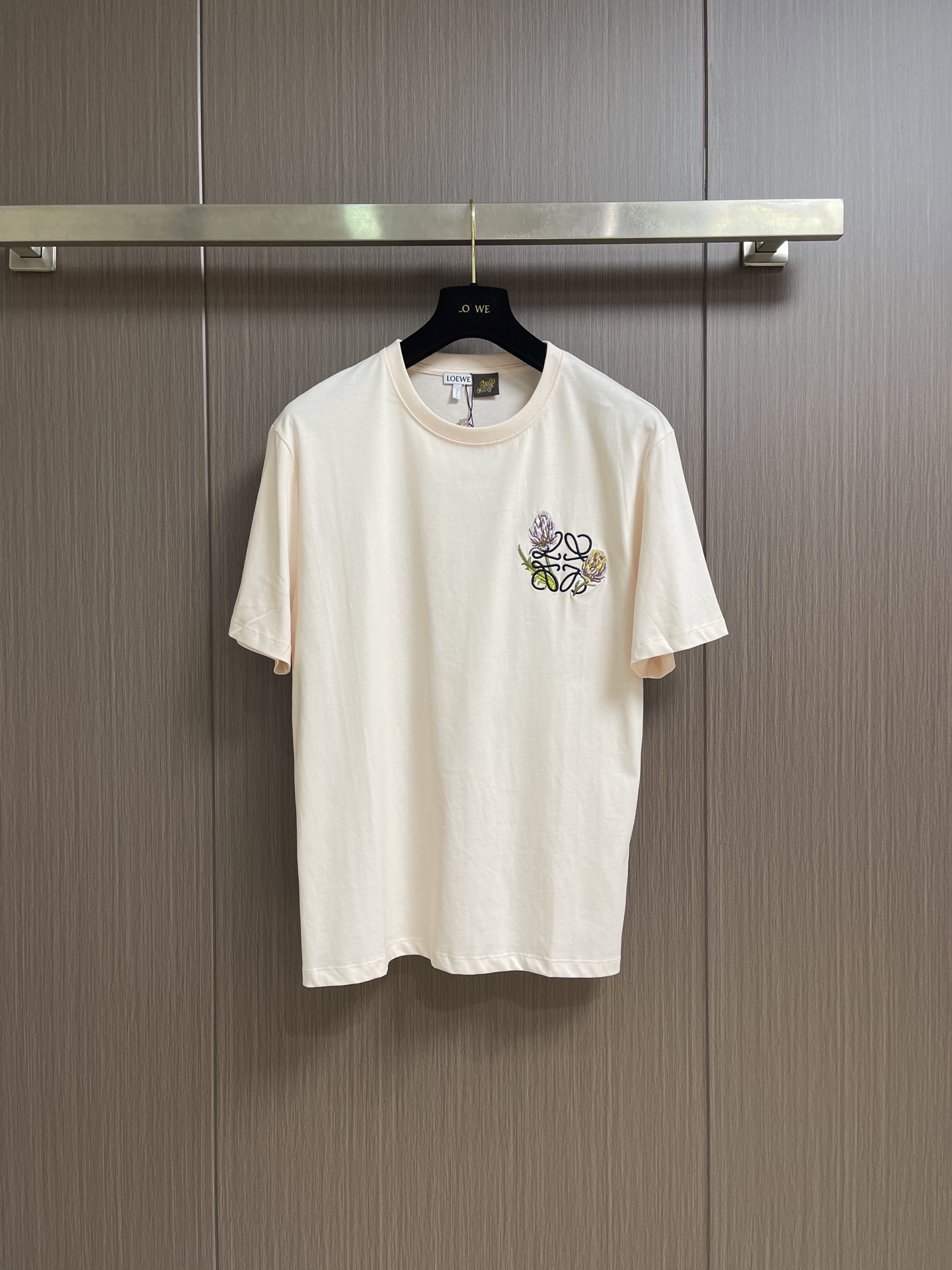 NO:837803,Loewe  Cotton Anagram flower embroidered T-shirt. This LOEWE short-sleeved T-shirt is made of high-count combed cotton fabric. The texture is soft and delicate, breathable and skin-friendly, and has good moisture absorption properties. It is smooth to the touch and not easy to deform. The classic round neck adopts reinforced hemming technology, the lines are smooth and fine, and the neckline is not easy to loose and deform after long-term wear. The brand flower embroidery on the left chest adopts precision three-dimensional embroidery technology, and the stitches are arranged evenly and tightly.  , the pattern outline is clear and full, the colors are rich, and the exquisite details are highlighted. The body adopts neat flat seam technology, the side seams are neatly routed, and the hem is solidly made. The overall tailoring is loose and smooth, taking into account both comfortable body feel and casual fit. It combines simple basic design with exquisite craftsmanship details, and has both daily wearability and high-end brand texture. The overall wiring is straight and delicate, the fabric is comfortable and soft, and the colors are consistent and without color difference.  It can be matched with the same style to create a fashionable look, and can be used in various occasions. Customized accessories, complete with three standards, same style for men and women!  Sizes XS-L19860909Loewe 棉质Anagram花朵刺绣T恤,本款LOEWE短袖T恤甄选高支精梳棉面料,质地柔软细腻,透气亲肤且具备良好吸湿性能,触感顺滑不易变形.经典圆领采用加固包边工艺,走线平整细密,领口久穿不易松垮变形；左胸品牌花卉刺绣采用精密立体绣制工艺,针脚排布均匀紧实,图案轮廓清晰饱满,色彩层次丰富,彰显精致细节.衣身采用利落平缝工艺,侧缝走线工整,下摆做工扎实,整体剪裁宽松流畅,兼顾舒适体感与随性版型,将简约基础款设计与精湛工艺细节融合,兼具日常实穿性与品牌高级质感.整体走线平直细腻,面料舒适柔软,颜色一致无色差 能与同款搭配营造时尚造型,驾驭各种场合,定制辅料,三标齐全,男女同款！尺码XS-L XS码胸围106肩宽48 衣长70 S码 胸围110 肩宽49.5 衣长72 M码胸围114 肩宽51衣长74 L码 胸围118 肩宽52.5衣长76,,loewe,T-shirt,tees，t-shirt,,Men's clothing