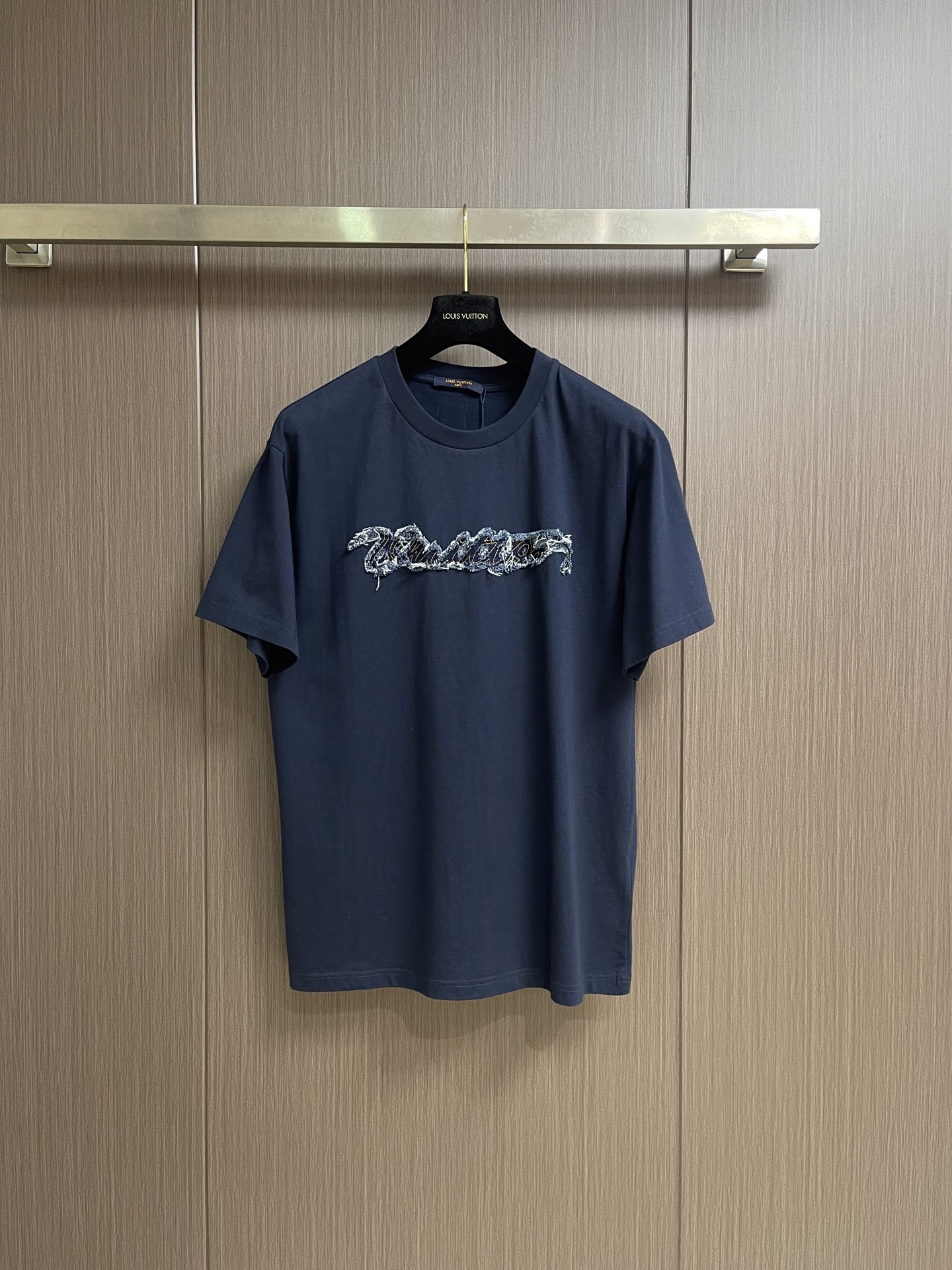 NO:842686,LV  The 2026ss new patch-embroidered short-sleeved T-shirt is made of 210g heavyweight combed cotton jersey fabric, which is treated with garment washing technology, giving the garment a soft and skin-friendly touch and a natural and soft retro texture, effectively improving the fabric's pilling resistance and dimensional stability. The body is cut with silhouetted shoulders, and is matched with a round neck and cuffs with double stitch reinforcement to achieve both comfort and durability. Chest  The front core decoration adopts laser cutting patch + flat embroidery overlocking process. The handwritten brand logo is precisely cut by laser, and the edges show a natural woolen effect. It is then fixed with contrasting stitching and flat embroidery. The edges of the patch are sanded and scattered to form a three-dimensional effect with rich layers of rough edges. It has both craftsmanship details and visual tension. It is a model of the combination of street retro style and high-end ready-to-wear craftsmanship. Sizes S-XL  Size S, bust 108, shoulder width 47, length 70, size M, bust 112, shoulder width 49, length 72, size L, bust 116, shoulder width 51, length 74, size XL, bust 120, shoulder width 53, length 76, Louis Vuitton, T-shirt, tees, t-shirt,19860909LV 2026ss新款贴布绣短袖T恤,甄选210g重磅精梳棉平纹针织面料,经成衣水洗工艺处理,赋予成衣软糯亲肤的触感与自然柔和的复古质感,有效提升面料抗起球性与尺寸稳定性.衣身采用廓形落肩剪裁,搭配二本针加固工艺的圆领与袖口,兼顾穿着舒适度与耐穿性.胸前核心装饰采用激光切割贴布+平绣锁边工艺,手写体品牌标识经激光精准裁切,边缘呈现自然毛絮效果,再以撞色车线平绣固定,贴布边缘做磨毛散边处理,形成层次感丰富的毛边立体效果,兼具工艺细节与视觉张力,是街头复古风格与高级成衣工艺的结合典范.尺码S-XL S码 胸围108肩宽47 衣长70 M码胸围112 肩宽49 衣长72 L码 胸围116 肩宽51衣长74 XL码胸围120 肩宽53 衣长76,,louis vuitton,T-shirt,tees，t-shirt,,Men's clothing