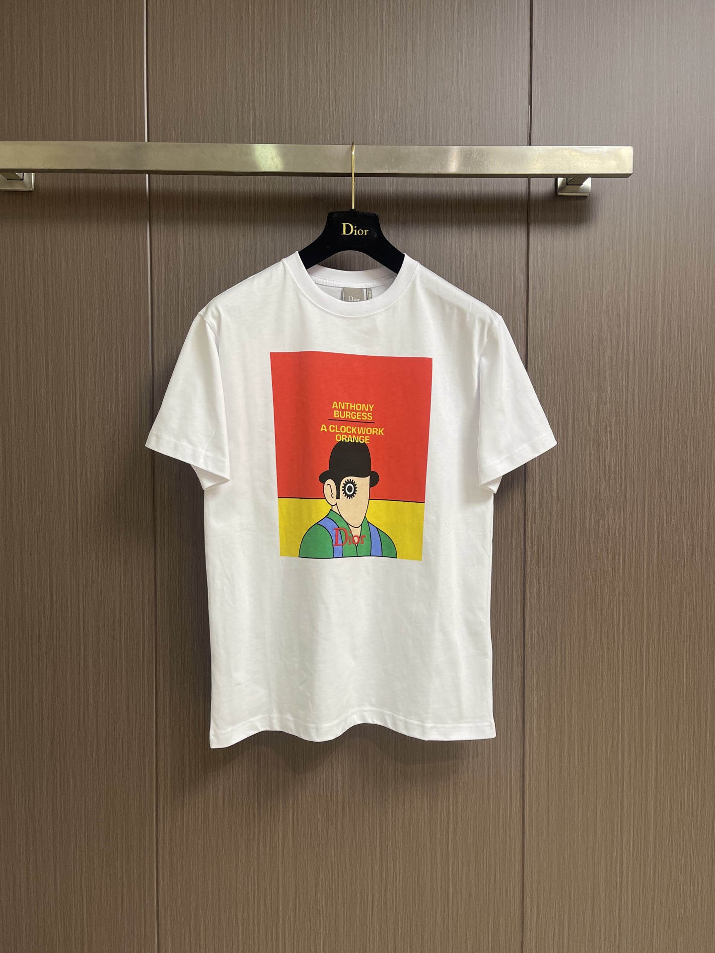 NO:842738,Dior The clockwork cover round neck short-sleeved T-shirt is made of 15-count special-spun compact cotton, 230gm pure cotton plain fabric, with 32-count 1×1 rib, 340gm. The 15-count special-spun compact cotton is a medium-low yarn count, and the yarn is thicker. The special-spun compact spinning process significantly reduces yarn hairiness, making the Thick-count yarn can also present a delicate and slightly matte cloth texture, while greatly improving the anti-pilling level. 32-count fine yarn combined with ultra-high weight makes the neckline extremely dense and thick. The front is decorated with the original cover pattern of 'A Clockwork Orange' using a penetration printing process; while specific letters are flat Penetration printing is essentially dye printing. Special additives are used to completely penetrate the dye molecules into the interior of cotton fibers and covalently bond with the fibers. Penetration printing requires high-precision color separation plate making to decompose the cover image into multiple color plates; printing During the process, dyes of various colors are sequentially scraped onto the fabric through the screen and solidified under the action of high-temperature steam. Penetration printing has extremely high color fastness and will not crack or fall off after washing, and will naturally become old along with the cotton fibers. The overall wiring is straight and delicate, the fabric is comfortable and soft, and the color is consistent without color difference. It can be matched with the same style to create a fashionable look, and can be used in various occasions. Customized accessories, complete with three standards, same style for men and women! Size XS-L19860909Dior 发条封面圆领短袖t恤,选用了15支特纺紧密棉,230gm的纯棉平纹面料,搭配32支1×1罗纹,340gm.15支特纺紧密棉属于中低纱支,纱线较粗.特纺紧密纺工艺显著减少了纱线毛羽,使粗支纱线也能呈现出细腻且微雾面的布面质感,同时大幅提升抗起毛球等级.32支细纱配合超高克重,使得领口极其致密厚重.正面饰以《发条橙》原版封面图案采用了渗透印花工艺；而特定字母则采用平针立体刺绣并以定位刺绣方式呈现渗透印花本质上是染料印花,通过特殊助剂使染料分子完全渗入棉纤维内部,与纤维发生共价键结合.渗透印花需要通过高精度分色制版,将封面图像分解为多套色版；印花过程中,各色染料依次通过丝网刮印到面料上,在高温蒸汽作用下固色.渗透印花的色牢度极高,水洗后不龟裂、不脱落,且会随着棉纤维一起自然做旧.整体走线平直细腻,面料舒适柔软,颜色一致无色差 能与同款搭配营造时尚造型,驾驭各种场合,定制辅料,三标齐全,男女同款！尺码XS-L XS码胸围102肩宽47衣长70 S码 胸围106肩宽48.5衣长72 M码胸围110 肩宽50衣长74 L码 胸围114 肩宽51.5 衣长76,,dior,T-shirt,tees，t-shirt,,Men's clothing