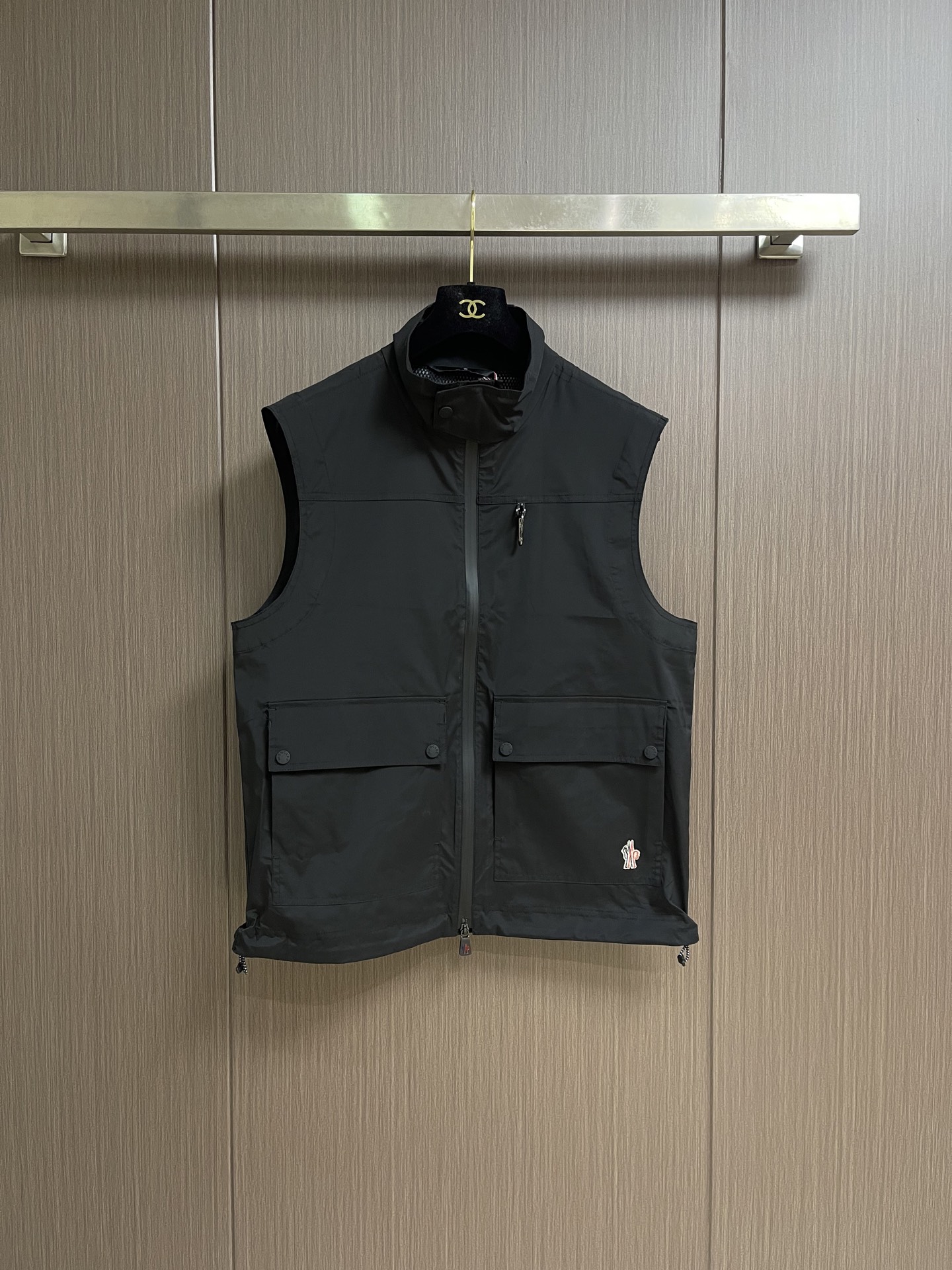 NO:847443,Moncler  The reflective logo outdoor vest is made of nylon as the main fabric, which has high-strength tear-resistant and abrasion-resistant properties, and the surface has undergone special wind- and water-repellent treatment. With the inner layer coating, it achieves 'wind-impermeable and water-impermeable' protection while retaining the lightweight nature of the fabric.  Wear it alone without feeling heavy and restrictive. The mesh lining is made of nylon + spandex blended breathable mesh. A small amount of spandex adds four-dimensional elasticity, which fits the shoulder and back lines without being tight, allowing unrestricted movement. It is not easy to deform or loose after stretching. The mesh texture has even gaps, smooth air circulation, and quick loosening.  The conductor surface is exposed to heat and moisture. The coating process combines the film with the fabric through hot-pressing lamination technology instead of ordinary glue to avoid the problem of film peeling and blistering after long-term wear. At the same time, the softness of the fabric is maintained and will not become stiff and hardened due to the coating. It uses thermosetting ink filaments.  For screen printing, the printer can deeply combine the ink with the fabric fibers through three scrapings. The printing has no glue feel, is not stiff, and is friction-resistant. It will not easily fall off due to daily wear and friction. The printing edges are sharp, there is no smudged burr, and the proportion of fonts and patterns is accurately restored. Reflective logo:  Through the reflective cloth punching process, the logo is regularly arranged on the triangular reflective mark with dozens of small holes, which improves functionality while strengthening recognition and aesthetics. Size 1-2-3-4 1 size shoulder width 47 bust 112 length 67 2 size shoulder width 48 bust 116 length 68.5 3 size shoulder width 49 bust 120 length 70 4 size  Shoulder width 50, bust 124, length 71.5,,19860909Moncler 反光标识户外马甲,采用锦纶主面料,其本身具备高强度抗撕裂、耐磨损特性,且表面经过特殊拒风拒水处理,配合内层覆膜,实现“风穿不透、水泼不进”的防护力,同时保留面料轻量化特质,成衣之后单穿无厚重束缚感.网眼内衬选用锦纶+氨纶混纺透气网眼,少量氨纶加持四维弹力,贴合肩背线条不紧绷,活动无拘束,拉伸后不易变形、不松垮.网眼肌理空隙均匀,空气循环通畅,快速疏导体表热气与湿气.覆膜工艺通过热压复合技术将薄膜与面料结合,而非普通胶水粘合,避免长期穿着后出现膜层脱落、起泡问题,同时保持面料的柔软度,不会因覆膜变得僵硬板结.采用热固油墨丝网印花,印花师通过3次刮印使油墨与面料纤维深度结合,印花无胶感、不发硬,且具备耐摩擦特性,日常穿着摩擦不会轻易脱落.印花边缘锐利,无晕染毛边,字体与图案比例精准还原.反光标识: 通过反光布冲孔工艺将Logo以数十个小孔规则排列呈现在三角形反光标之上,提升功能性的同时强化了辨识度和美观性.尺码1-2-3-4 1码肩宽47胸围112衣长67 2码 肩宽48胸围116衣长68.5 3码 肩宽49胸围120衣长70 4码 肩宽50胸围124衣长71.5,,,Men's clothing