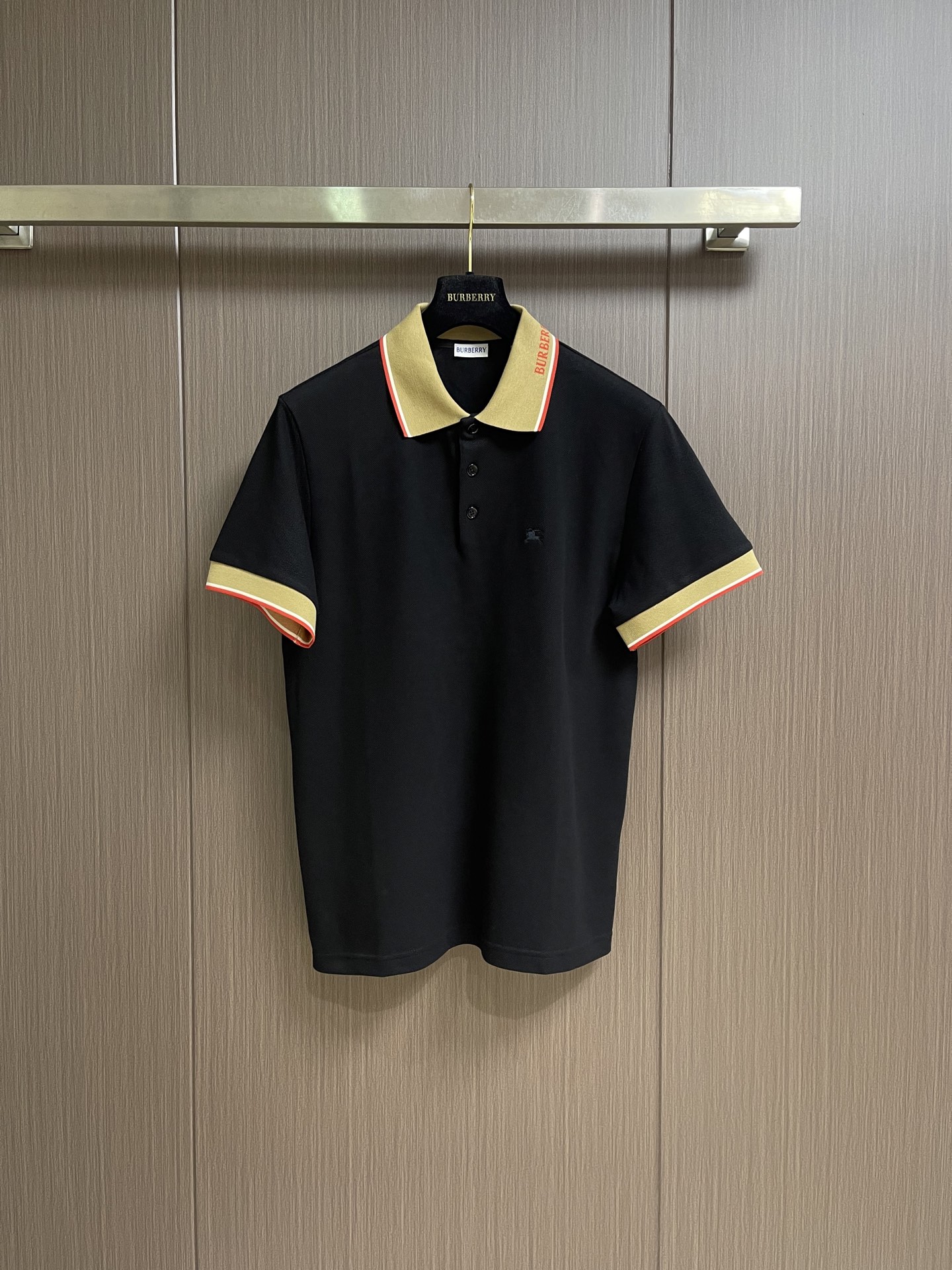NO:847440,Burberry  The letter logo short-sleeved POLO shirt uses cotton as the base and a small amount of elastic fiber blended pique fabric. It forms a concave and convex mesh texture through a special knitted coil structure. Each group of coils is interlaced with each other to form a breathable 'small honeycomb' structure. The feeding of elastic fibers greatly improves the wrinkle resistance of the fabric, and it is not easy to leave marks when folded at will. It is always smooth and neat for daily wear. At the same time, the pique texture is fine and layered, and the visual effect is  It feels matte and low-key, soft to the touch but not sinewy. Iron the front of the fabric flat in advance, accurately mark the embroidery position, install the embroidery frame on the machine, and align the center point of the pattern. Use high-saturation embroidery thread and pass it through high-density filling needles. The stitches are fine and even, making the knight and war horse pattern clear and layered, visually embossed and not easy to deform. After finishing, the edges of the pattern are smooth, without hard edges, and there is no foreign body feeling when worn against the skin.  The letters on the collar side are integrated into the jacquard weaving process instead of post-printing or embroidery. The letters and contrasting stripes are directly formed by the loom. The lines are clear and neat, with no redundant burrs on the edges. The pattern is integrated with the fabric, and it is not easy to fall off and crack after repeated friction and machine washing. It uses high-permeability resin buttons with a smooth surface and no burrs. The letter logo is engraved in the center of the button. The texture is high-end and wear-resistant. The overall wiring is straight and delicate, the fabric is comfortable and soft, and the color is consistent without color difference.  Can be matched with the same style to create a fashionable look, control various occasions, customized accessories, complete three standards, the same style for men and women. Sizes S-XL 46-52 46 yards, shoulder width 47, bust length 68.5, 48 yards, shoulder width 48, bust 112, length 70 50 yards, shoulder width 49, bust 116, length 71.5 52 yards  Shoulder width 50, bust 120, length 73, burberry, T-shirt,19860909Burberry 字母标识短袖POLO衫,选用棉为基底喂入少量弹性纤维混纺而成的珠地布面料,通过特殊的针织线圈结构形成凹凸的网眼纹理,每一组线圈相互交错,构成透气的“小蜂巢”结构.弹性纤维的喂入,大幅提升面料抗皱性,随意折叠也不易留痕,日常穿着始终平整利落.同时珠地纹理细腻且富有层次,视觉上哑光低调,触感柔软却不失筋骨.将面料前幅,提前熨烫平整,精准标记刺绣位置,将绣花框装入机台,对齐图案中心点.选用高饱和度绣线通过高密度填充针,针脚细密均匀,使骑士与战马图案轮廓清晰,层次分明,视觉上有浮雕感,不易变形.后整理之后,图案边缘平滑,无硬边,贴肤穿着无异物感 领侧的字母采用一体提花织入工艺,而非后期印花或刺绣,字母与撞色条纹均通过织机直接成型,线条清晰利落、边缘无冗余毛边,图案与面料融为一体,反复摩擦、机洗也不易脱落开裂.采用高透树脂纽扣,表面光滑无毛刺,纽扣中心刻有字母标识,质感高级且耐磨.整体走线平直细腻,面料舒适柔软,颜色一致无色差 能与同款搭配营造时尚造型,驾驭各种场合,定制辅料,三标齐全,男女同款.尺码S-XL 46-52 46码 肩宽47胸围衣长68.5 48码 肩宽48胸围112衣长70 50码 肩宽49胸围116衣长71.5 52码 肩宽50胸围120衣长73,,burberry,T-shirt,,Men's clothing
