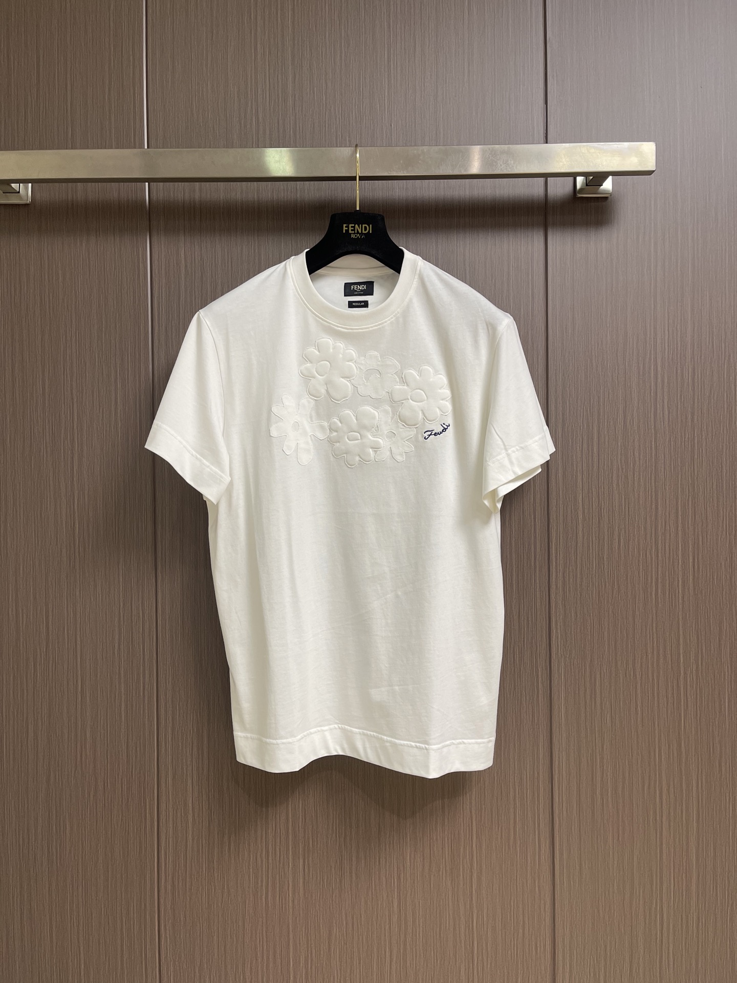 NO:847423,Fendi  The round-neck short-sleeved T-shirt with patchwork embroidery is made of pure cotton with a weight of 220g. It is derived from natural cotton fiber. It has a soft and delicate touch, is skin-friendly and non-irritating, and can be worn by sensitive skin with peace of mind. Using 20S1 compact spinning process, the yarn has less hairiness, even sliver, clear and regular texture, and visual  It is more refined and high-end. At the same time, it retains the natural breathable pores of cotton fiber and has excellent moisture absorption and perspiration effects. Compared with ordinary plain cotton, the dense cotton cloth is more wear-resistant, less prone to pilling, and more durable for daily wear. The same color high-gloss embroidery thread is used, and the stitches are closely arranged through high-precision operation of the embroidery machine.  There are no jumps or missed stitches. The edges of the logo are clear and sharp, showing a three-dimensional and full visual effect. When touching, you can feel the uniform raised texture, solid and layered; the embroidery area is accurately located in the center of the lower back collar, with coordinated proportions and no offset, skew and other problems. The flowers are decorated with blue  The embroidery is made of colorful polyester fiber embroidery thread, forming a soft contrast with the white background. The handwritten embroidery restores the original brushstroke details, with smooth and natural lines; the embroidery stitches are fine and firm, and will not easily come off or turn white after being worn for a long time. The overall threading is straight and delicate, the fabric is comfortable and soft, and the colors are consistent without color difference.  It can be matched with the same style to create a fashionable look, and can be used in various occasions. Customized accessories, complete with three standards, same style for men and women!  Size S-XL 46-52 46 yards shoulder width 47 bust 106 length 68 48 yards shoulder width 48 chest 110 length 69.5 50 yards shoulder width 49 chest 114 length 71 52 yards shoulder width 50 chest 118 length 72.5,, fendi, T-shirt, tees, t-shirt,19860909Fendi 贴布绣花圆领短袖t恤,选用纯棉材质,克重达220g,源自天然棉纤维,触感柔软细腻,亲肤不刺激,敏感肌也能安心穿着.采用20S1紧密纺工艺,纱线毛羽少、条干均匀,纹理清晰规整,视觉上更显精致高级.同时保留了棉纤维的天然透气孔,吸湿排汗效果出色相比普通平纹棉,紧密棉的布面更耐磨、不易起球,日常穿着更耐造.选用同色系高光泽绣线,通过绣花机高精度作业,针脚紧密排列无跳线、漏针现象,标志边缘清晰锐利,呈现出立体饱满的视觉效果,触摸时能感受到均匀的凸起质感,扎实且富有层次；刺绣区域精准位于后领下方中央,比例协调,无偏移、歪斜等问题.花朵旁饰以蓝色聚酯纤维绣线刺绣,与白色底色形成柔和撞色,手写体的刺绣还原了原版的笔触细节,线条流畅自然；刺绣针脚细密牢固,久穿不易脱线、不易发白.整体走线平直细腻,面料舒适柔软,颜色一致无色差 能与同款搭配营造时尚造型,驾驭各种场合,定制辅料,三标齐全,男女同款！尺码S-XL 46-52 46码 肩宽47胸围106衣长68 48码 肩宽48胸围110衣长69.5 50码 肩宽49胸围114衣长71 52码 肩宽50胸围118衣长72.5,,fendi,T-shirt,tees，t-shirt,,Men's clothing