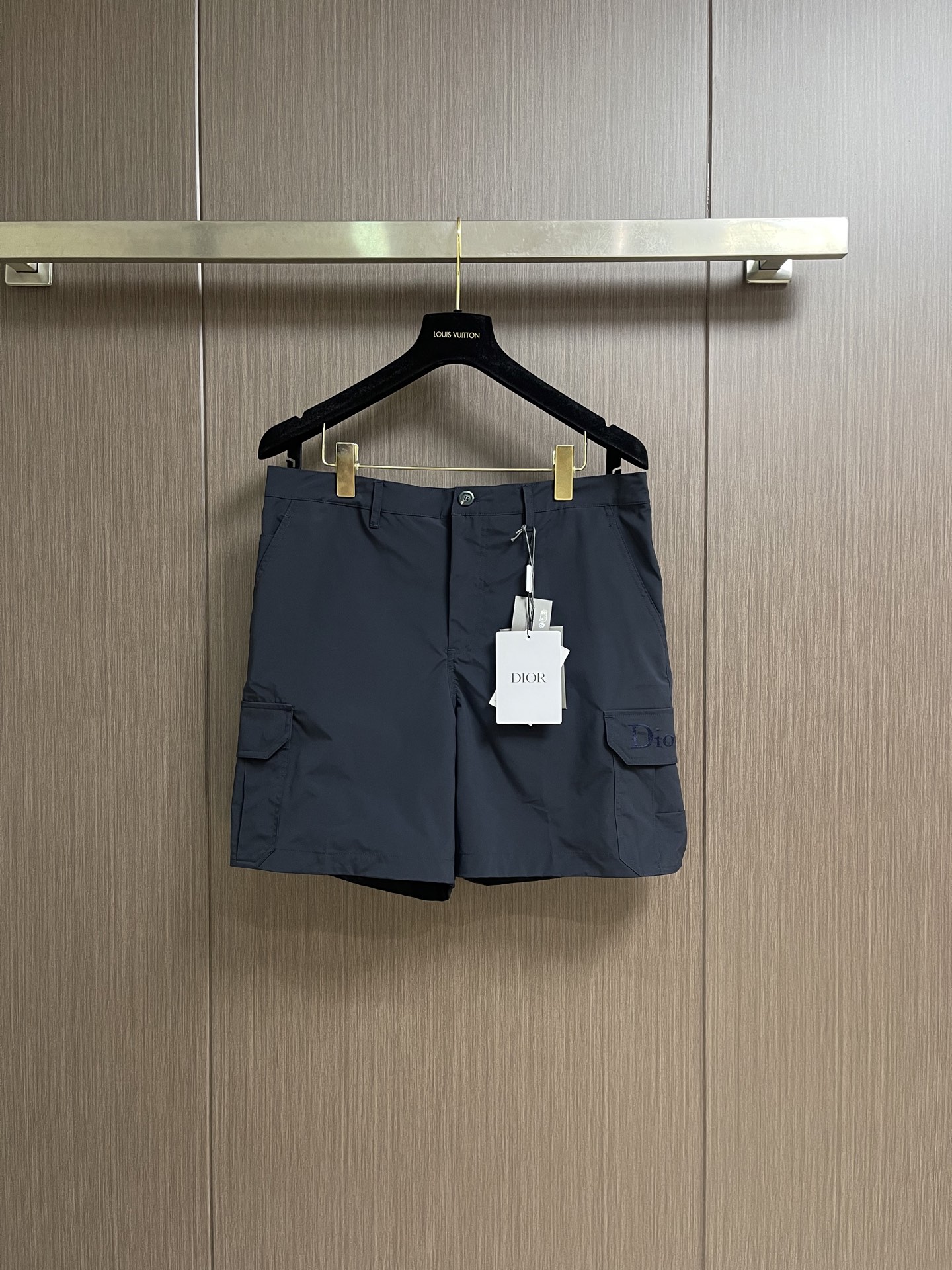 NO:847419,Dior  Solid color embroidered work shorts. These navy blue work shorts are made of high-count cotton blended twill fabric, treated with liquid ammonia-free ironing and anti-wrinkle finishing. They feel crisp and smooth, have good breathability and anti-wrinkle properties, and are not easily deformed after long-term wear. The waist adopts a classic button closure design with adjustable straps. The placket adopts double-thread overlocking technology, with fine and even stitching, which effectively improves structural strength and durability. Large sizes on both sides  The three-dimensional workwear pockets adopt three-dimensional tailoring and reinforced stitching, and the edges of the pockets are hemmed to prevent the fabric from going off-line. The same color embroidery process is used above the right pocket to present the brand logo. The stitching is exquisite and three-dimensional, and the pattern is clear and full. The trouser legs are made of flat-cut seaming technology, and the overall shape is neat and stylish, taking into account the practical functions of workwear and the exquisite texture of light luxury. The overall routing is straight and delicate, the fabric is comfortable and soft, and the colors are consistent and without color difference.  It can be matched with the same style to create a fashionable look, and can be used in various occasions. Customized accessories, complete with three standards, same style for men and women!  Size S-XL 46-52 46 yards, waist 84, seat 102, pants length 41, 48 yards, waist 88, seat 106, pants length 42, 50 yards, waist 92, seat 110, pants length 43, 52 yards, waist 96, seat 114, pants length 44,,dior,shorts,19860909Dior 纯色刺绣工装短裤,这款藏青色工装短裤采用高支棉混纺斜纹面料,经液氨免烫与抗皱整理工艺处理,触感挺括顺滑,兼具良好的透气性与抗皱性,久穿不易变形.腰头采用经典的纽扣式闭合设计,搭配可调节袢带,门襟处采用双线包缝工艺,针脚细密均匀,有效提升结构强度与耐用性.两侧大尺寸立体工装口袋采用立体剪裁与加固车线,袋口边缘做包边处理,防止面料脱线,右侧口袋上方采用同色系刺绣工艺呈现品牌标识,针脚细腻立体,图案清晰饱满.裤脚采用平切锁边工艺,整体版型利落有型,兼顾了工装的实用功能与轻奢的精致质感.整体走线平直细腻,面料舒适柔软,颜色一致无色差 能与同款搭配营造时尚造型,驾驭各种场合,定制辅料,三标齐全,男女同款！尺码S-XL 46-52 46码 腰围84坐围102 裤长41 48码 腰围88坐围106 裤长42 50码 腰围92坐围110 裤长43 52码 腰围96坐围114 裤长44,,dior,shorts,,Men's clothing