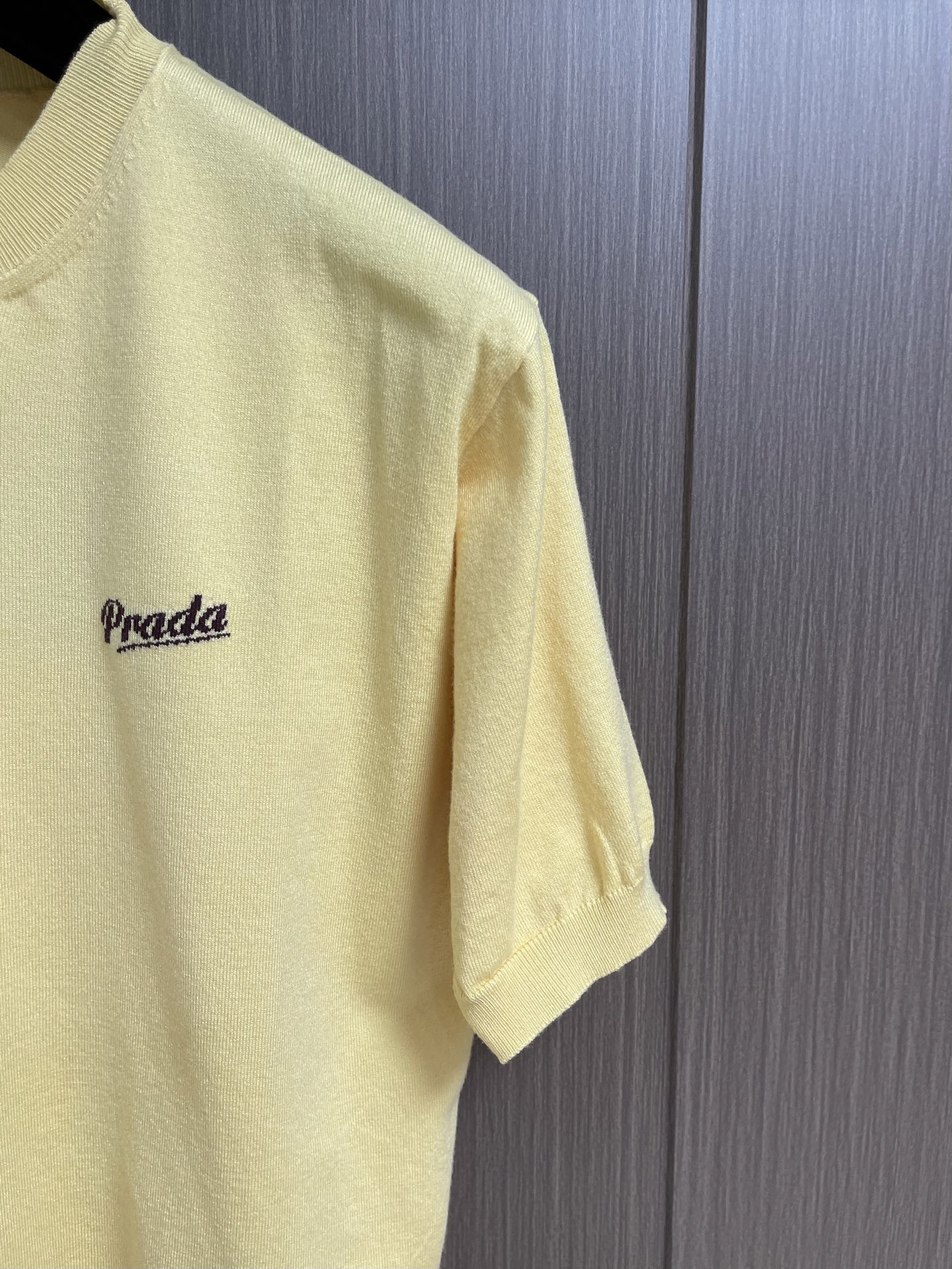 Prada 徽标嵌花圆领短袖针织毛衣，定织柔滑双股高密棉毛纱，柔软蓬松，舒适贴肤。以低饱和苋菜黄为基调，