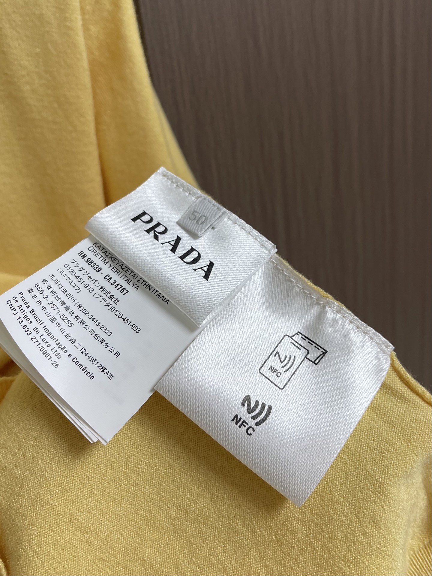 Prada 徽标嵌花圆领短袖针织毛衣，定织柔滑双股高密棉毛纱，柔软蓬松，舒适贴肤。以低饱和苋菜黄为基调，
