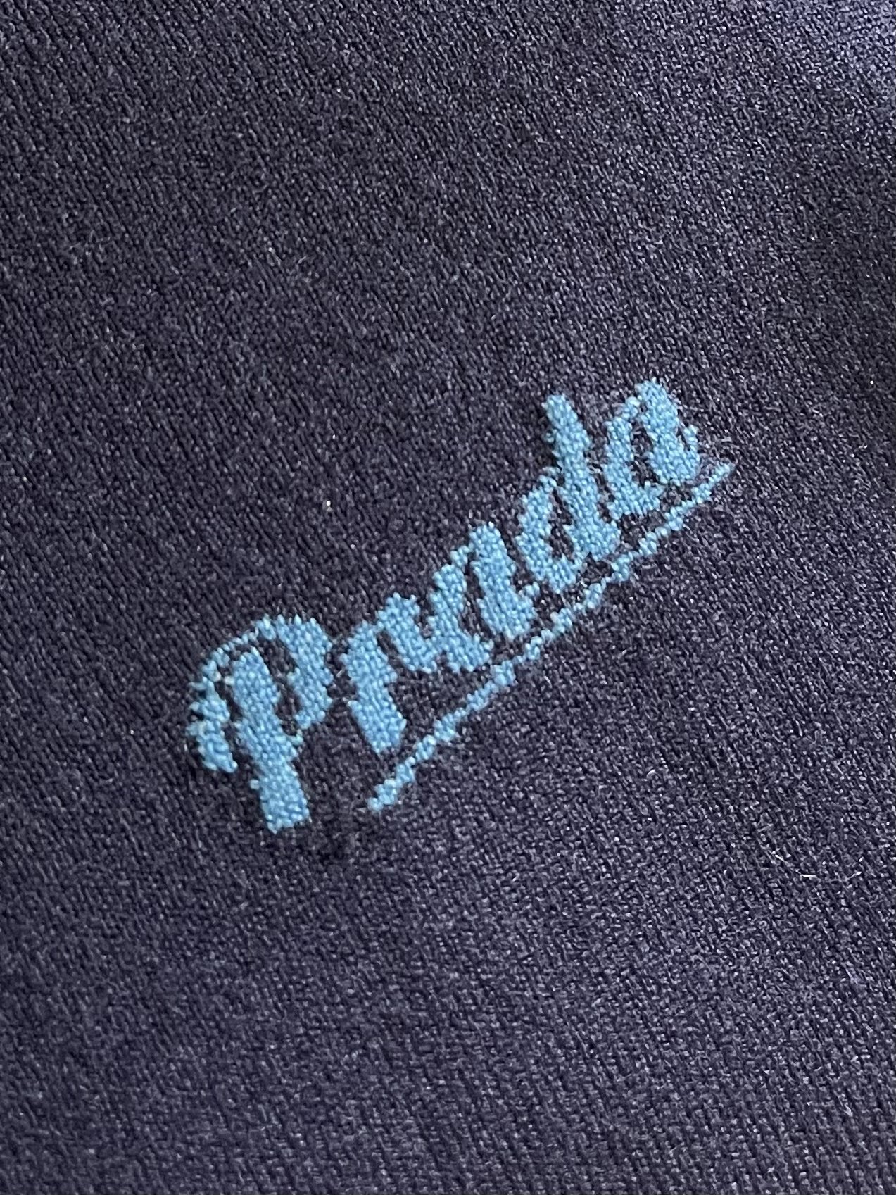 Prada 徽标嵌花圆领短袖针织毛衣，定织柔滑双股高密棉毛纱，柔软蓬松，舒适贴肤。以低饱和苋菜黄为基调，