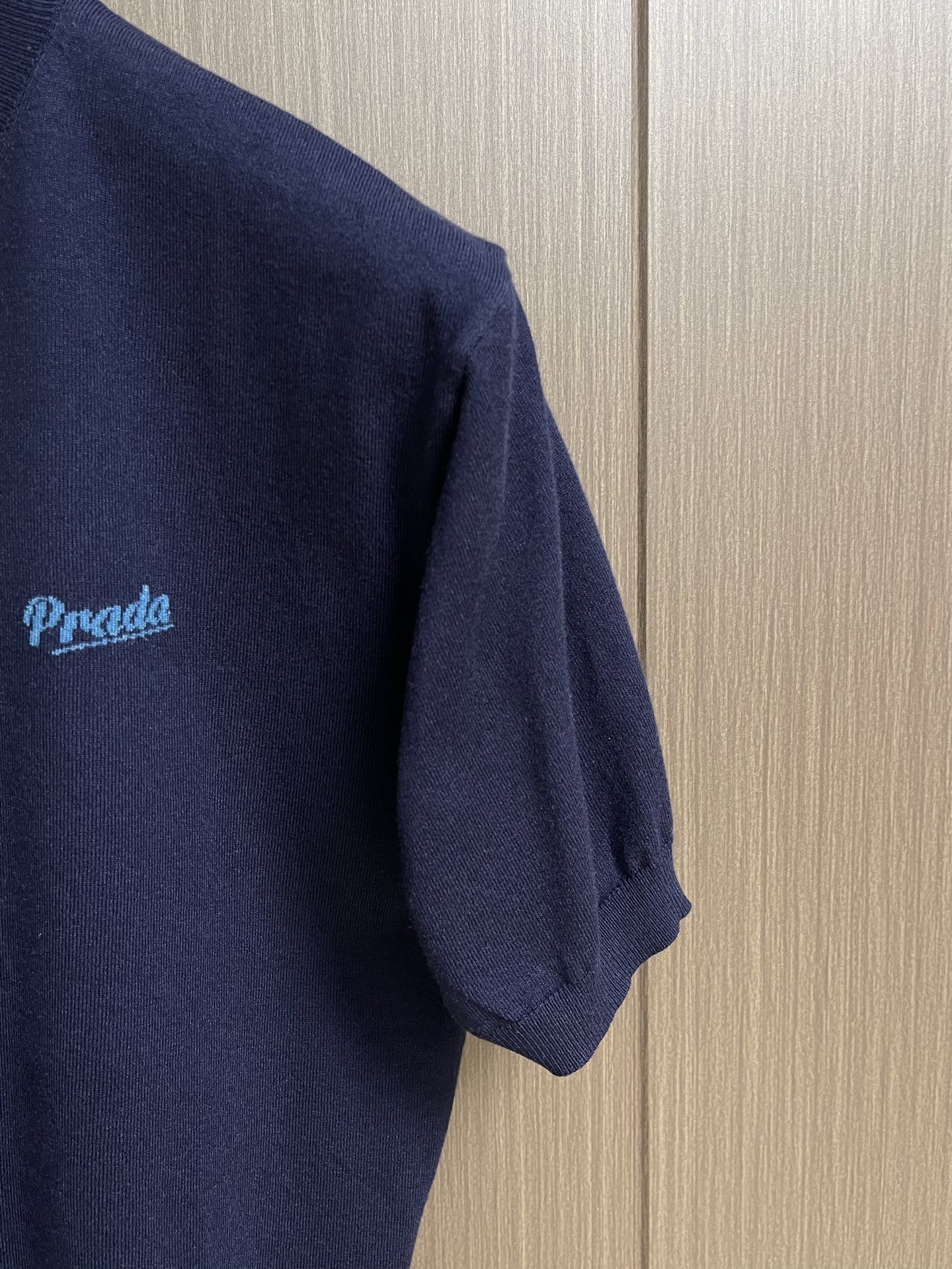 Prada 徽标嵌花圆领短袖针织毛衣，定织柔滑双股高密棉毛纱，柔软蓬松，舒适贴肤。以低饱和苋菜黄为基调，