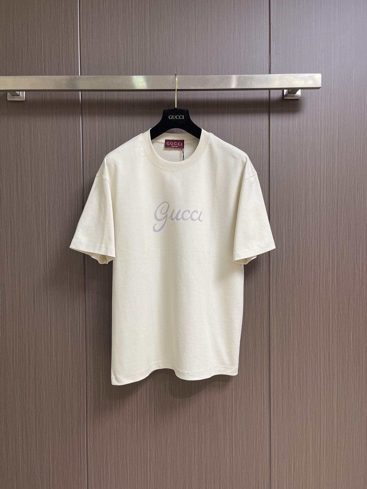 NO:903970,Gucci  Retro distressed short-sleeved T-shirt with handwritten letters. The classic off-white tone is selected to create a light and luxurious casual short-sleeved shirt. The handwritten Gucci logo on the front panel + the retro medal square logo on the back panel are double-sided printed design, blending Italian retro accents with modern relaxed fit.  , is the basic old-money style T-shirt that high-end wear circles just need. It is the same style for men and women and can be worn with any body shape. It is selected from heavyweight long-staple double yarn cotton and processed through pre-shrunk washing + liquid nitrogen softening. The texture of the fabric is delicate and soft, and it is both firm and skin-friendly.  Attributes of style. Double version of retro distressed offset printing on the front and back, using heavy-duty whitening retro cracking process, the natural wear and tear texture of middle-aged vintage clothing, the casual handwritten Gu** on the front, the brushstrokes are smart and freehand; the red-edged retro medal square on the back  The logo contains the crown emblem and the classic words FIRENZE·SINCE1921. The red and brown edges outline the retro outline. The ink penetrates the fabric fibers and is washable without cracking. It restores the time-precipitated feeling of antique printing. Size XS-L  XS size shoulder width 52 bust 108 length 69 S size shoulder width 53 bust 112 length 71 M size shoulder width 54 bust 116 length 73 L size shoulder width 55 bust 120 length 75, gucci, T-shirt, tees, t-shirt,19860909Gucci 复古做旧手写字母短袖T恤,甄选经典米白基调打造轻奢休闲短袖,前幅手写花体Gucci标识+后幅复古勋章方标双面印花设计,将意式复古腔调与现代松弛版型融合,是高阶穿搭圈刚需的老钱风基础T,男女同款百搭不挑身形.精选重磅长绒双纱棉,经过预缩水洗+液氮柔化双重工艺处理,布面肌理细腻软糯,兼顾扎实挺括度与亲肤透气属性.前后双版复古做旧胶印,采用重工磨白复古龟裂工艺,中古vintage成衣自然磨损质感,前襟随性手写花体Gu**,笔触灵动写意；后背红边复古勋章方标,内含皇冠徽纹、FIRENZE·SINCE1921经典字样,红棕包边勾勒复古轮廓,油墨渗透面料纤维,耐洗不开裂,还原古董印花的岁月沉淀感.尺码XS-L XS码肩宽52胸围108 衣长69  S码肩宽53胸围112衣长71  M码 肩宽54胸围116衣长73 L码 肩宽55胸围120衣长75,,gucci,T-shirt,tees，t-shirt,,Men's clothing