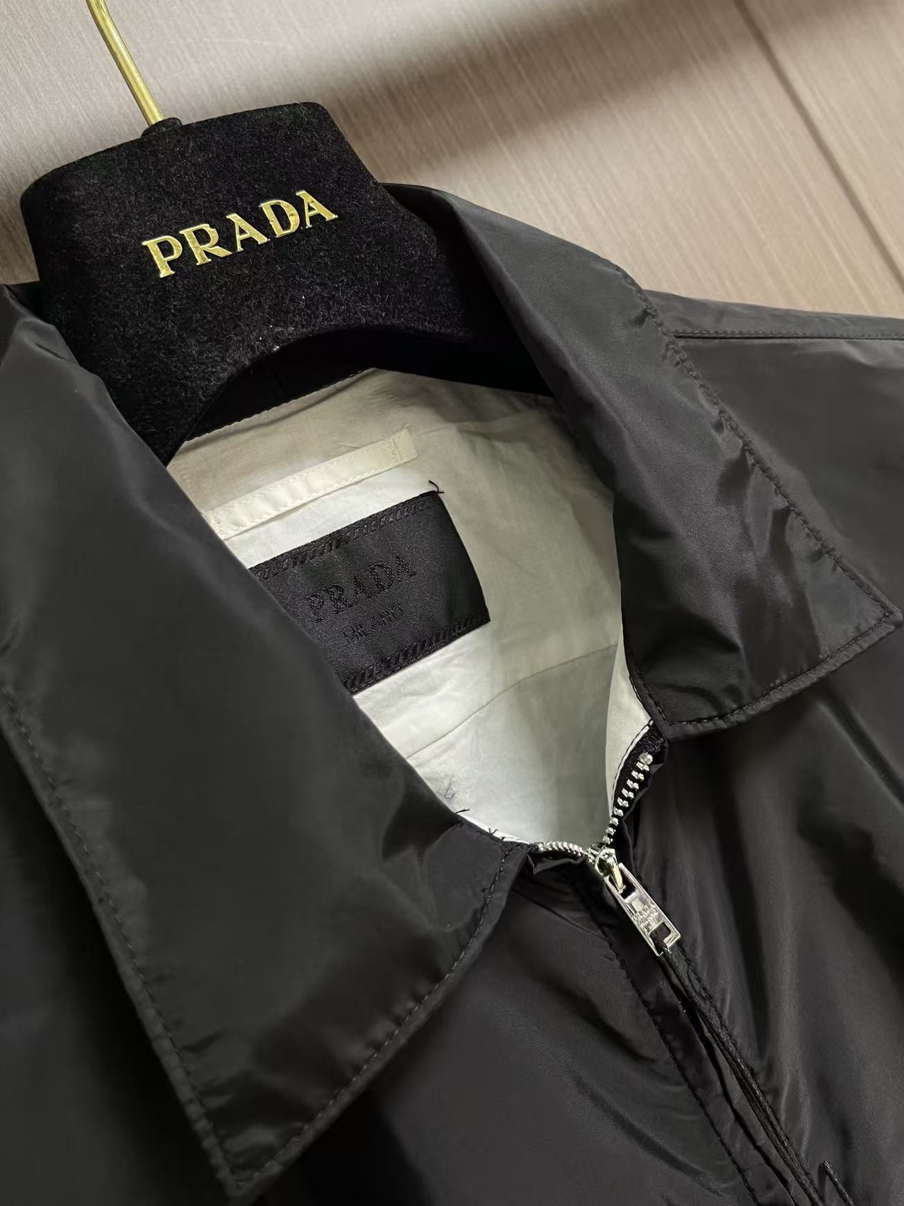 Prada 饰标翻领小外套，精选高密织造尼龙面料，纤维肌理紧实饱满，整体质地轻盈轻薄，上身零负重。面料经