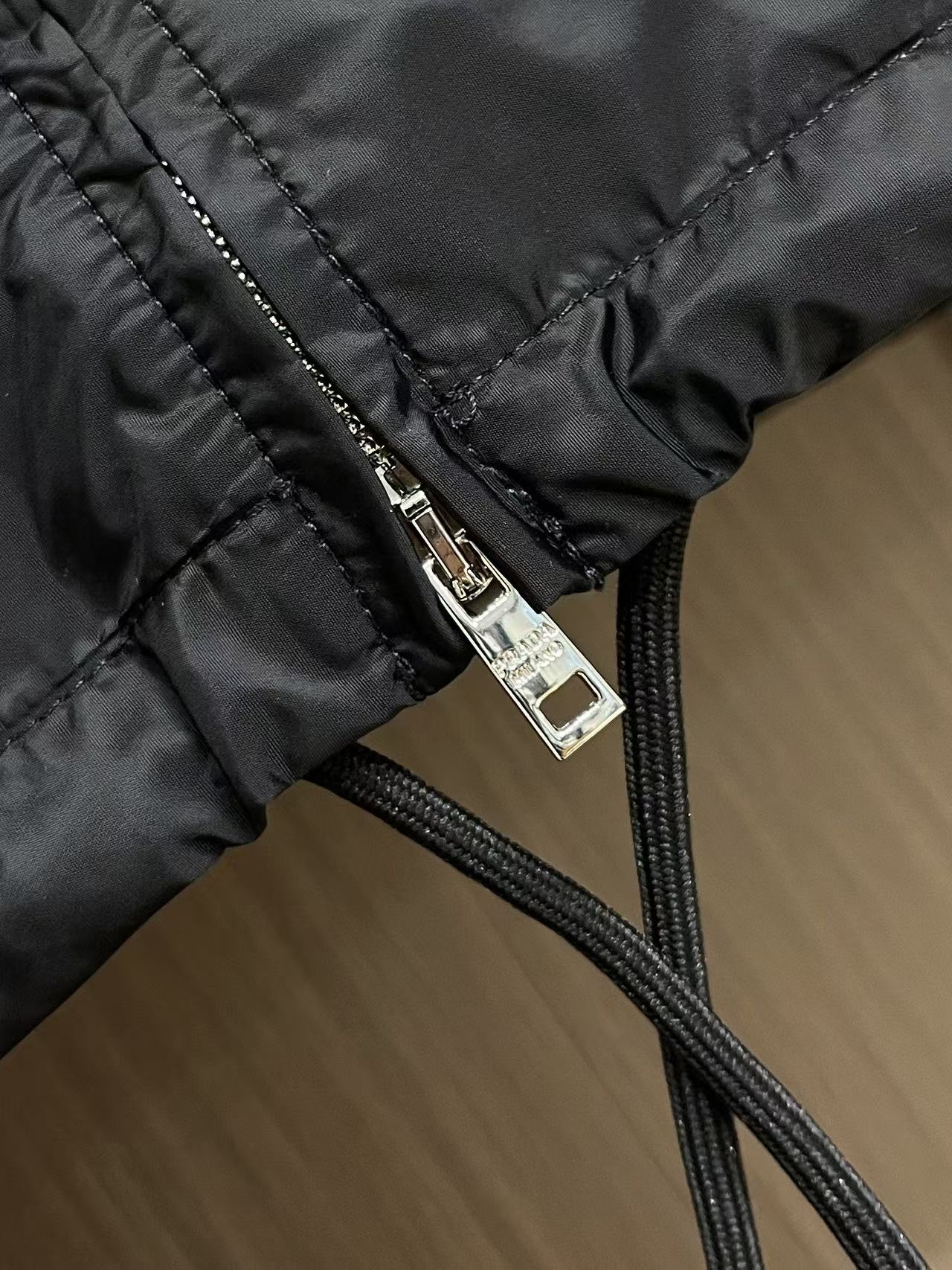 Prada 饰标翻领小外套，精选高密织造尼龙面料，纤维肌理紧实饱满，整体质地轻盈轻薄，上身零负重。面料经
