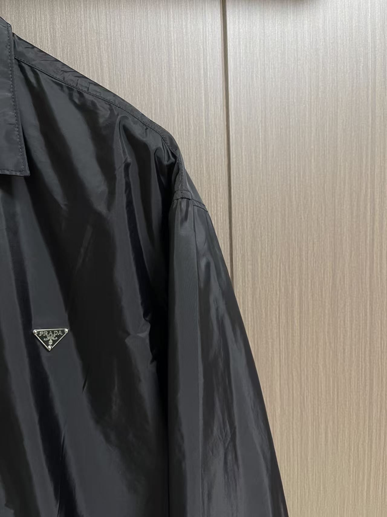 Prada 饰标翻领小外套，精选高密织造尼龙面料，纤维肌理紧实饱满，整体质地轻盈轻薄，上身零负重。面料经